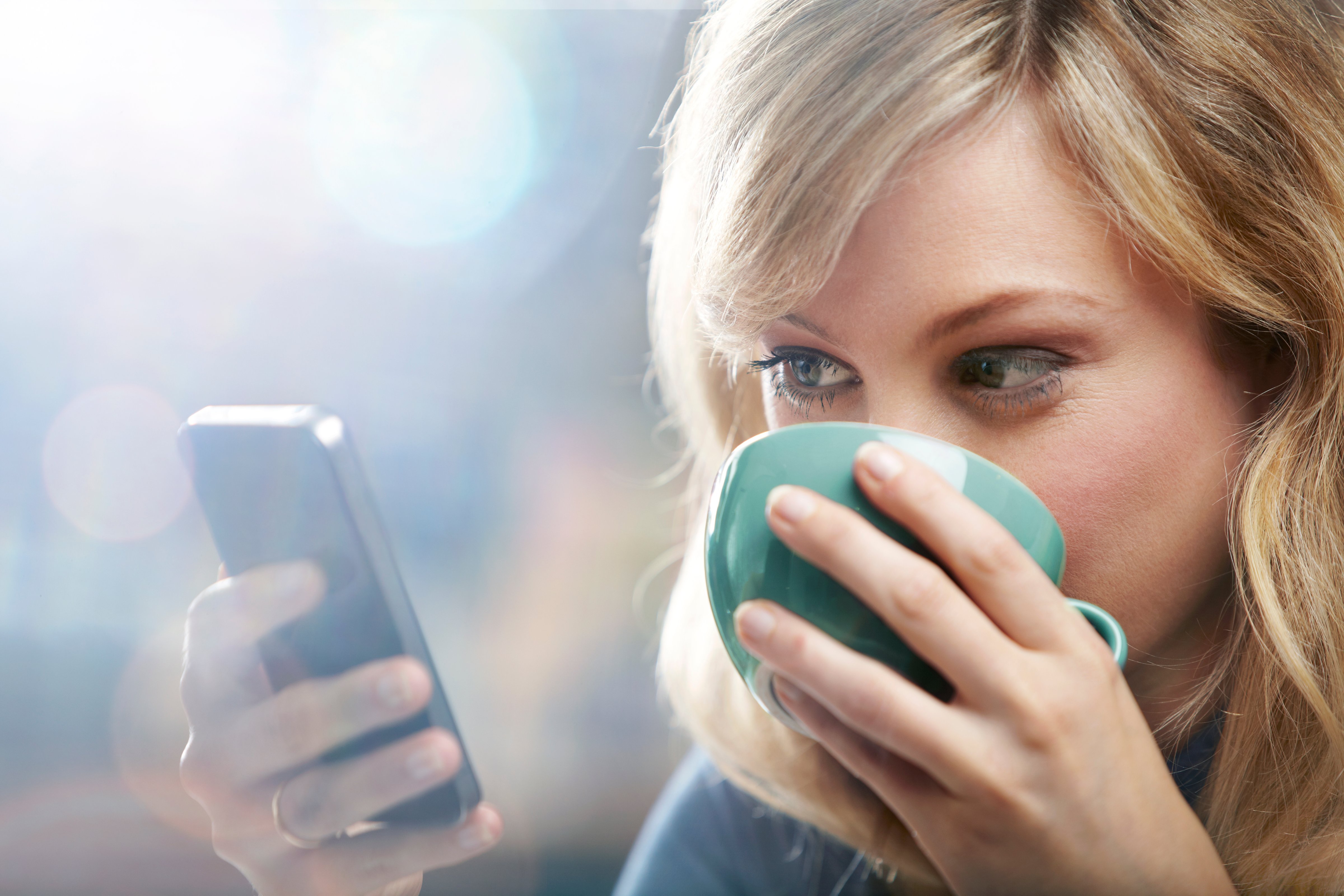 Woman using phone and drinking coffee (Oli Kellett&mdash;Getty Images)