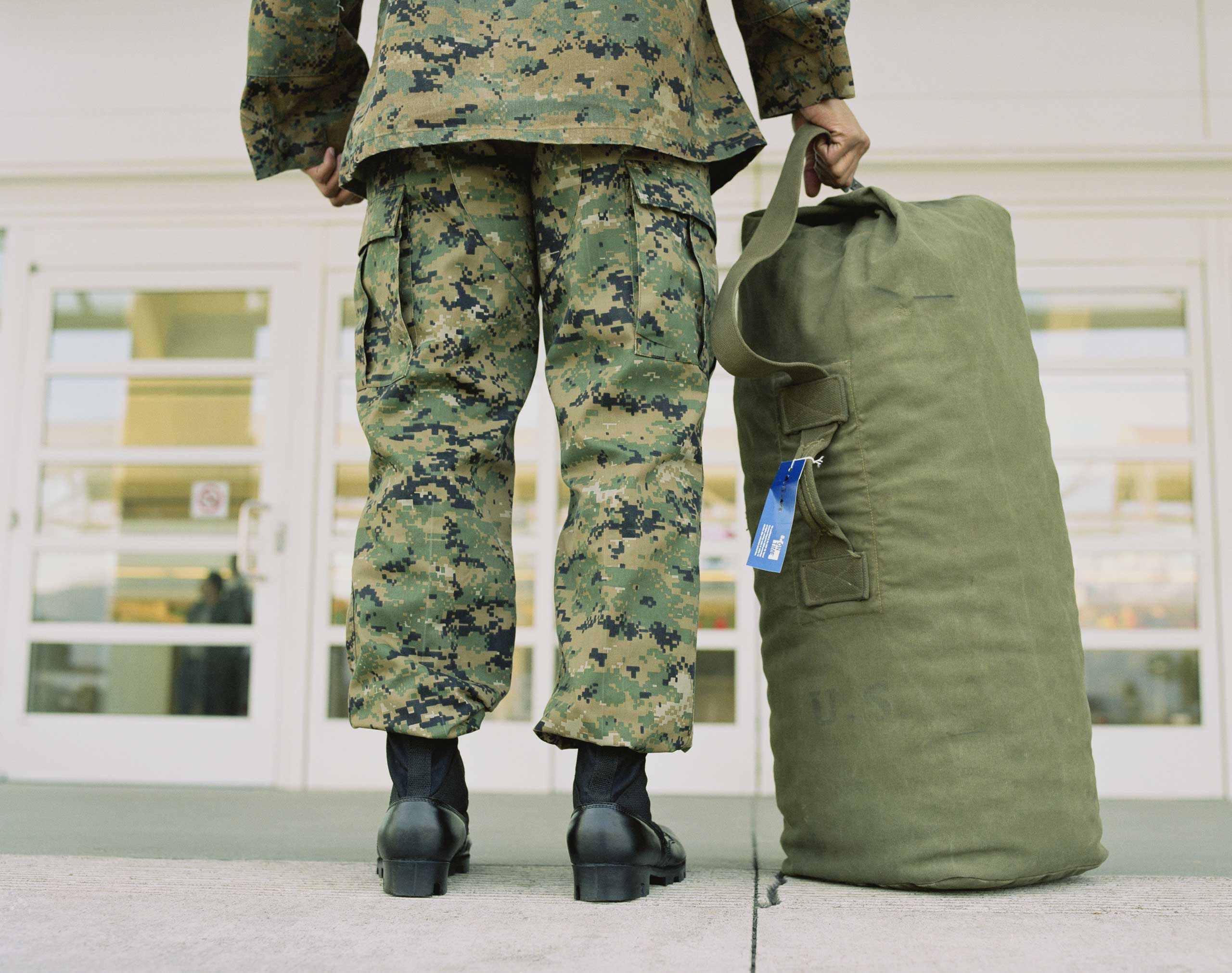 Military soldier with bag in airport, low section