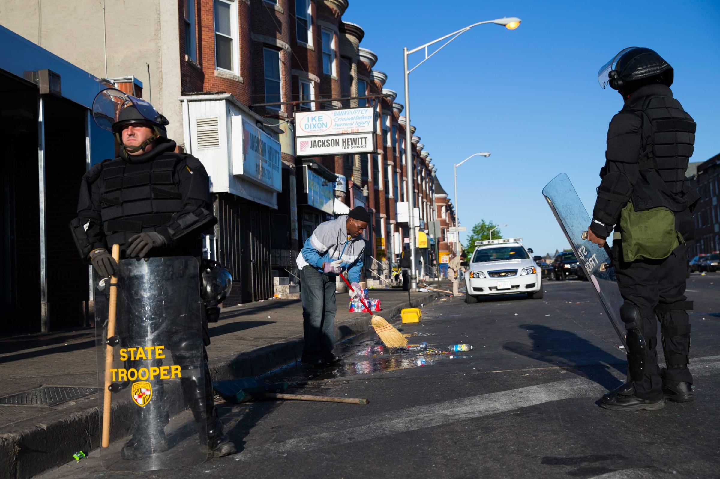 Maryland state troopers stand guard as residents clean up after a night of riots in Baltimore on April 28, 2015.