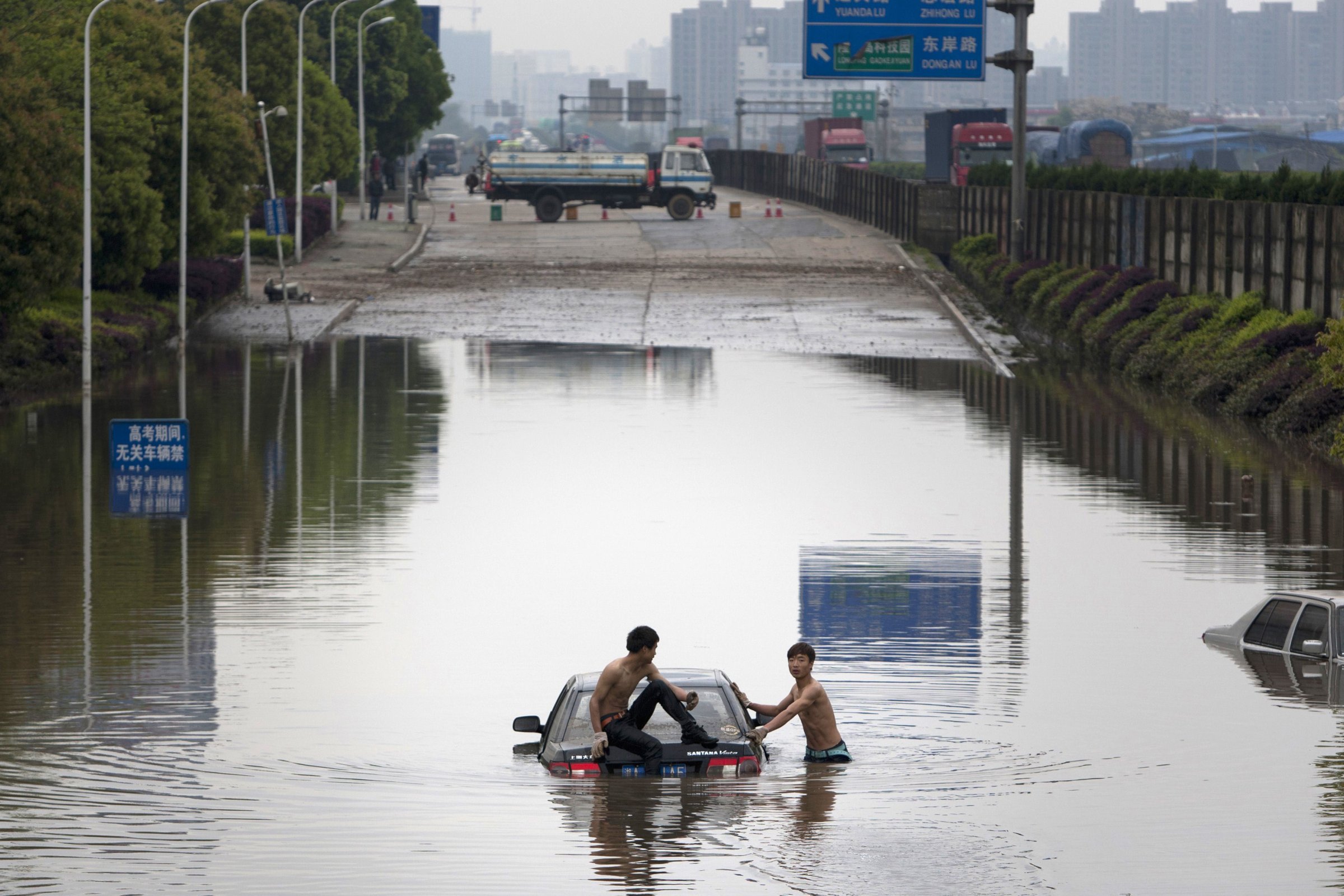 This picture shows two men attempting to push a car out of floodwaters after a storm swept Changsha, central China's Hunan province on taken on April 7, 2015