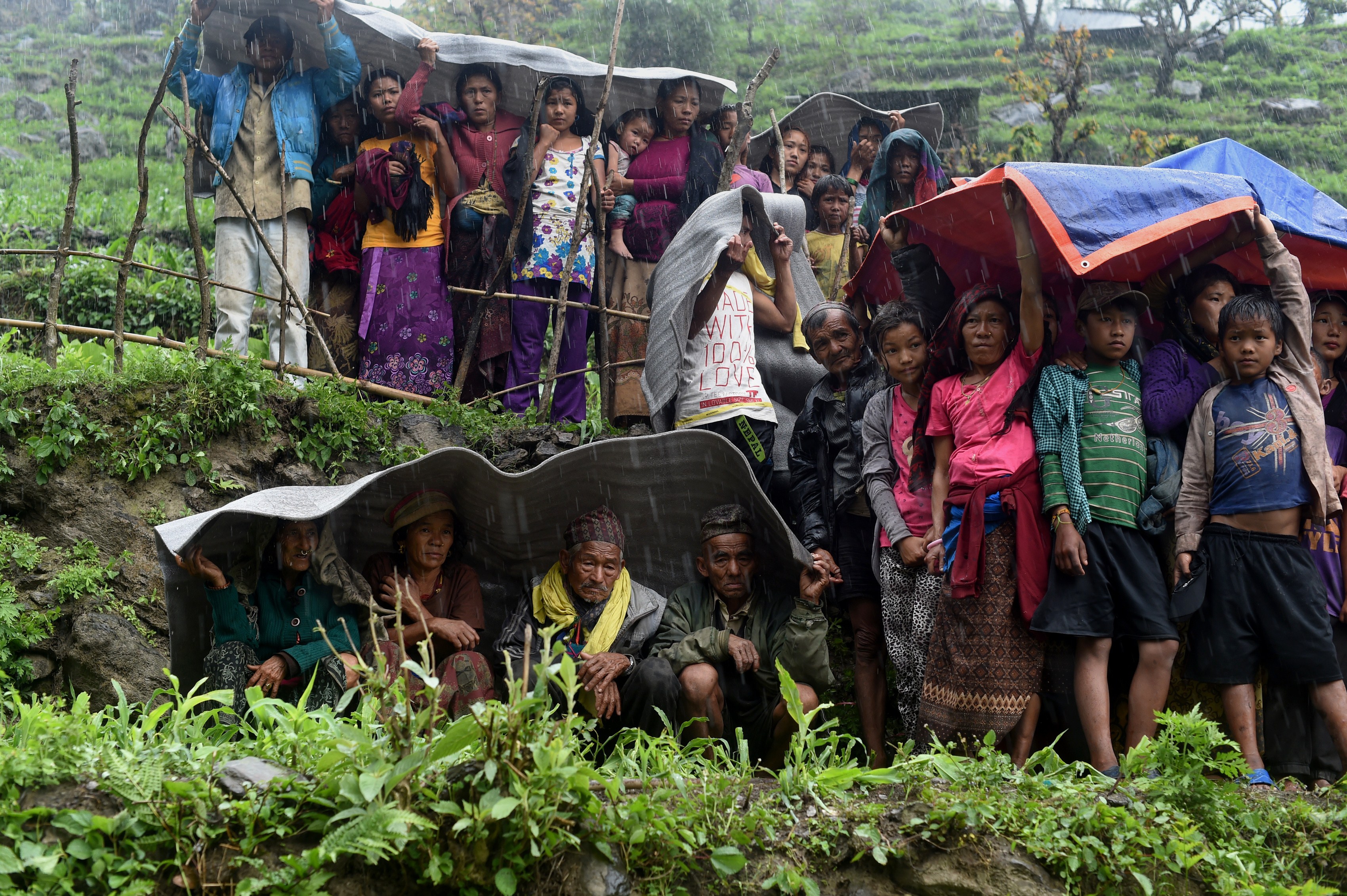 Nepalese villagers shelter from rain as an Indian Army helicopter delivers aid following an earthquake at Lapu in Gorkha on April 28, 2015. The impoverished country's leader said relief workers had still not reached many of the worst-hit areas. (SAJJAD HUSSAIN—AFP/Getty Images)