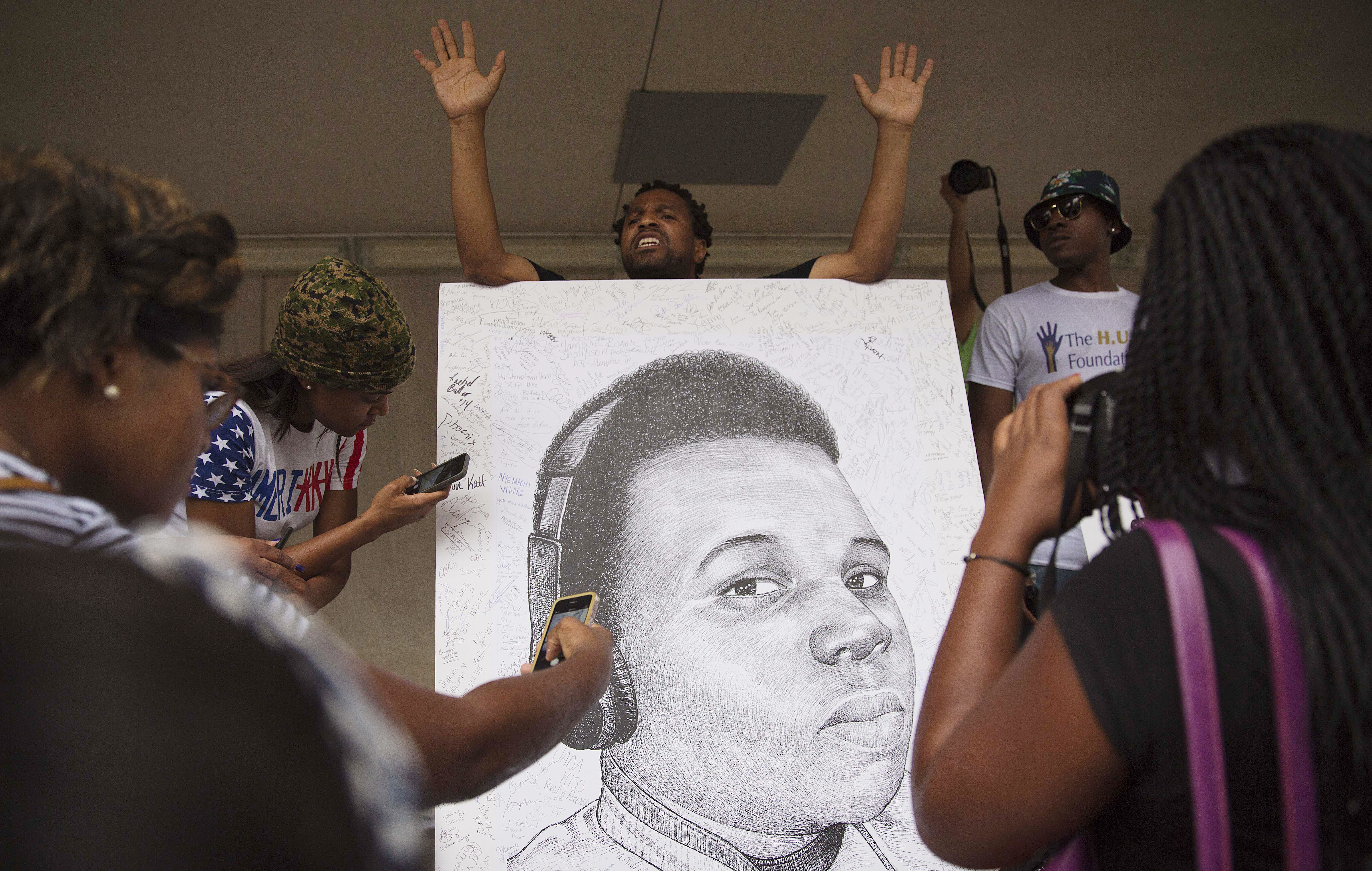 Demonstrators autograph a drawing of Michael Brown during a protest against the fatal police shooting, in Atlanta on Aug. 18, 2014.