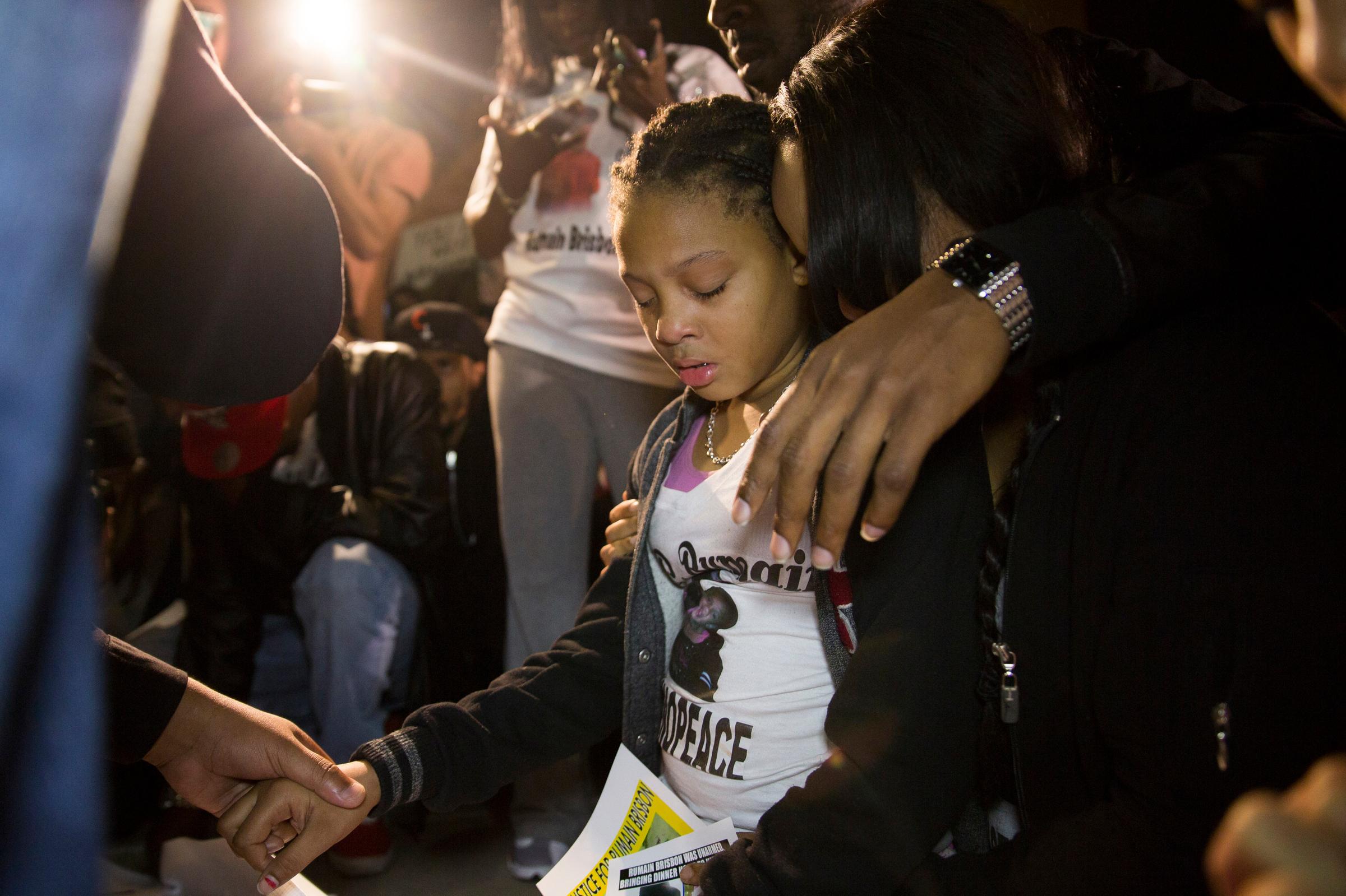 The daughter of Rumain Brisbon (L) begins crying as she kneels in prayer at a vigil for her father who was fatally shot by police, in Phoenix, Ariz. on Dec. 8, 2014.