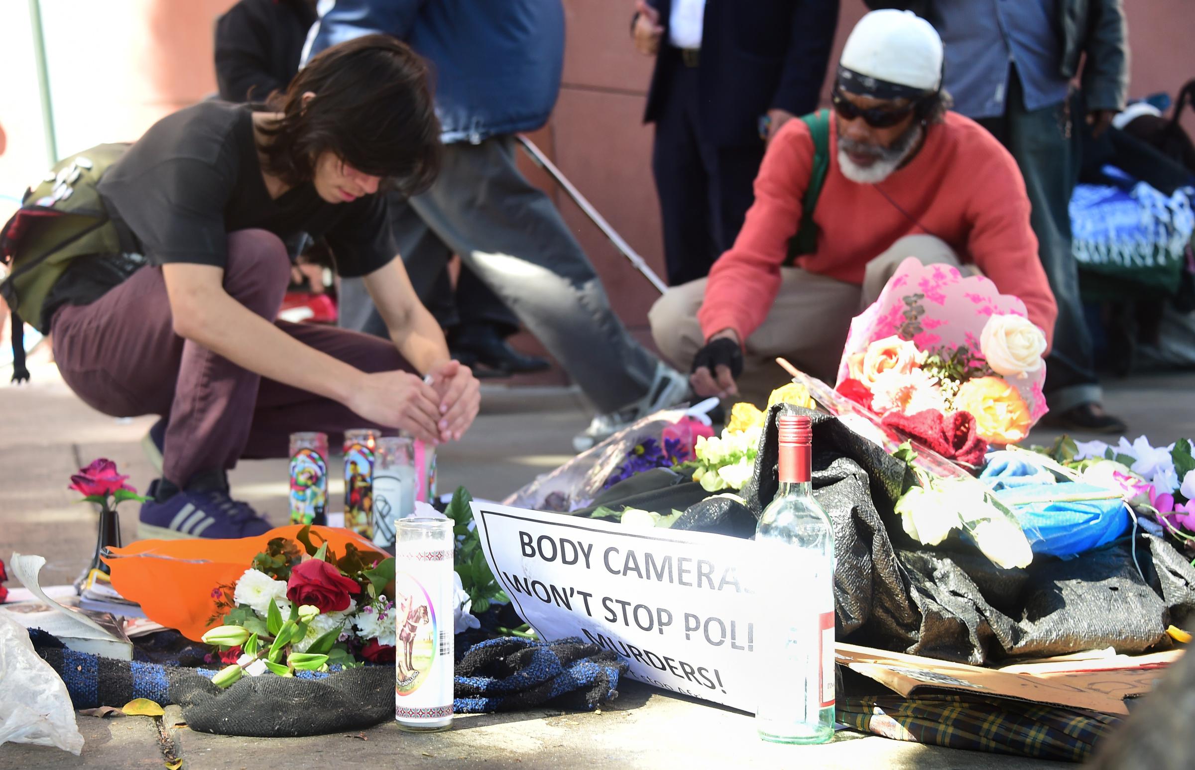 People pay their respects at an ever-growing makeshift memorial where a homeless man known as "Africa" who was shot by police, in Los Angeles on March 3, 2015.