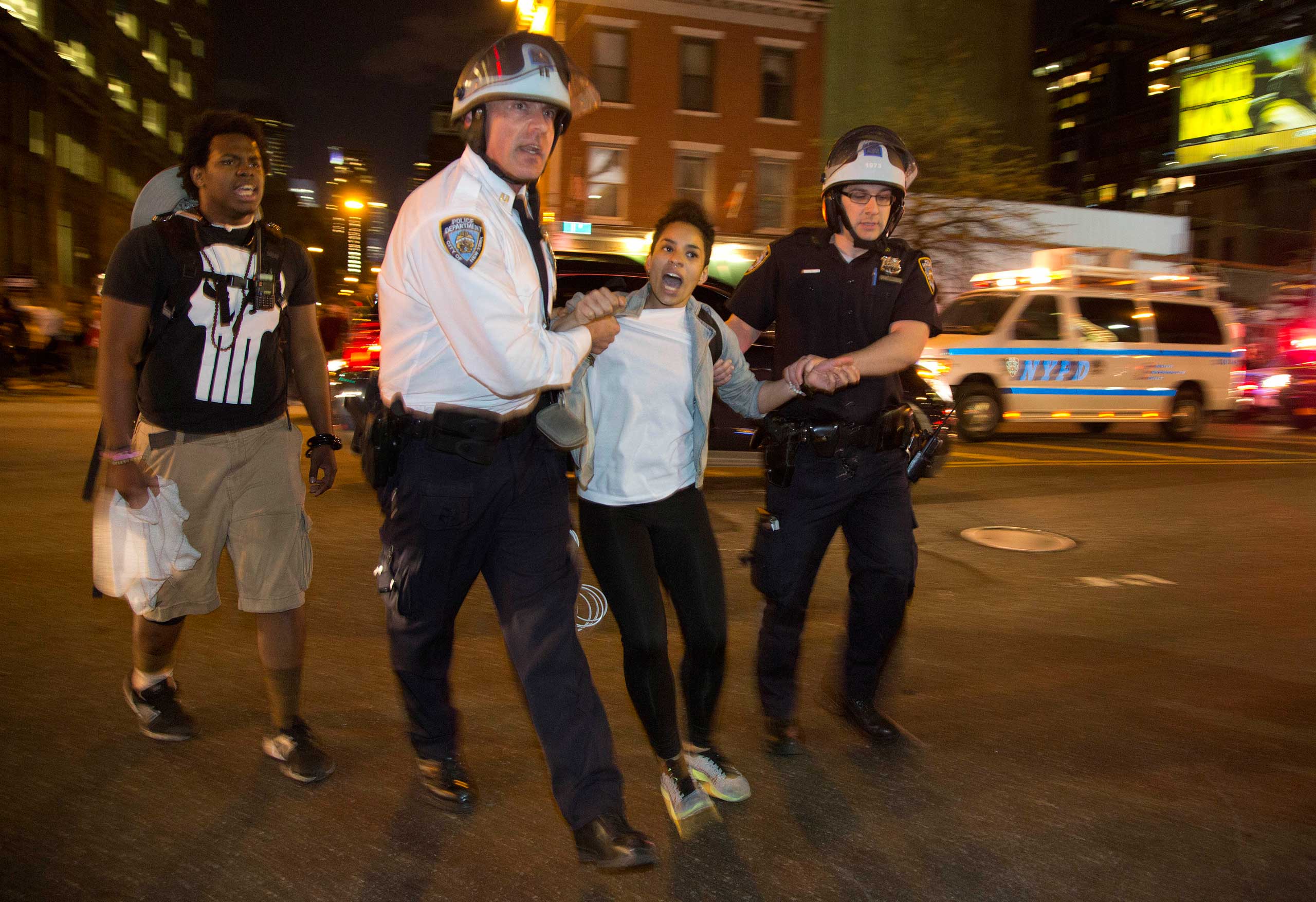 New York City police escort a woman off the street and back onto the sidewalk where she was released during a protest in New York City on April 29, 2015.