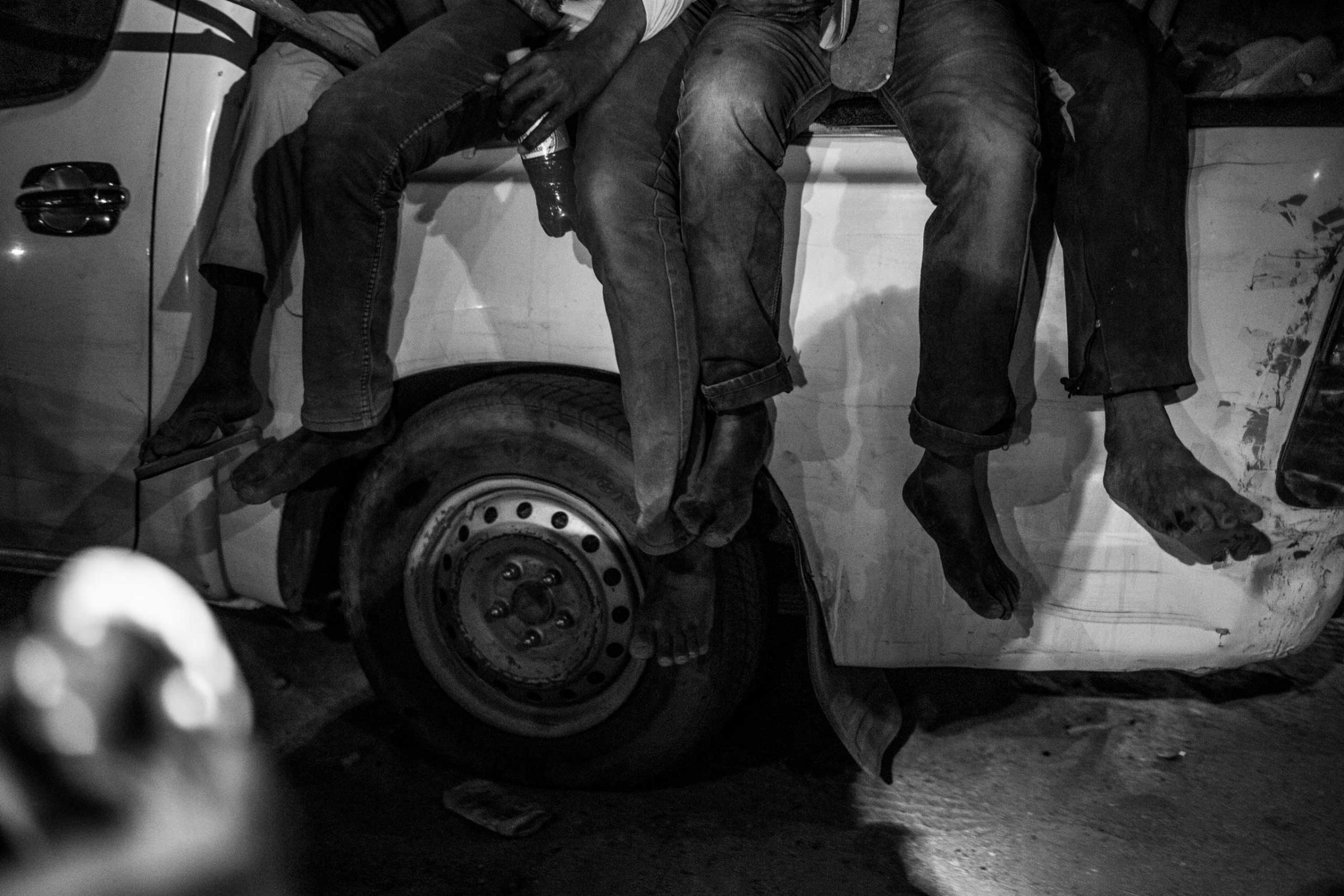 The barefeet of migrants hang from the back of a pickup truck carrying them to Libya.