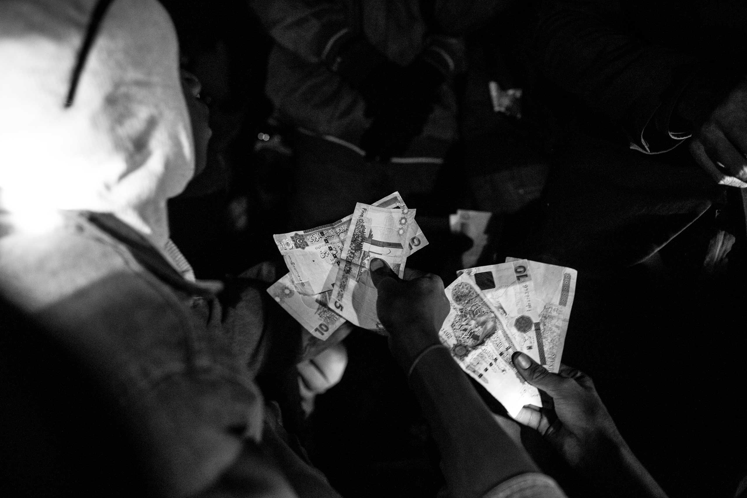 Migrants change money to Libyan Dinars. Each migrant pays 150,000 West African CFA Francs (roughly $250) for their journey north.