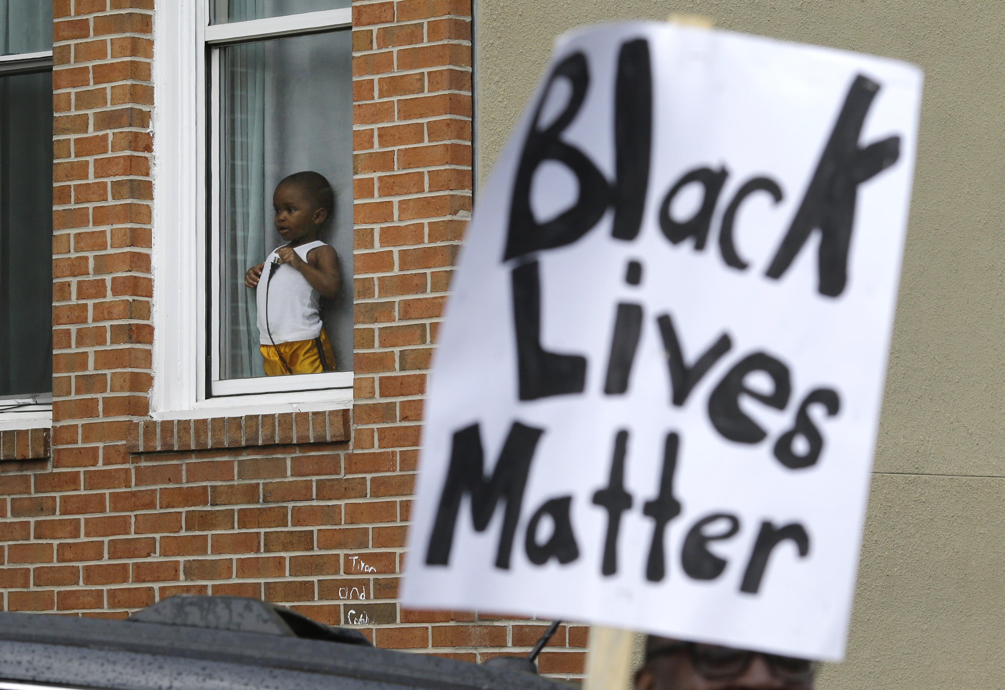 A child watches a protest march for Freddie Gray as it passes by April 22, 2015, in Baltimore. Gray died from spinal injuries about a week after he was arrested and transported in a police van. (Patrick Semansky—AP)