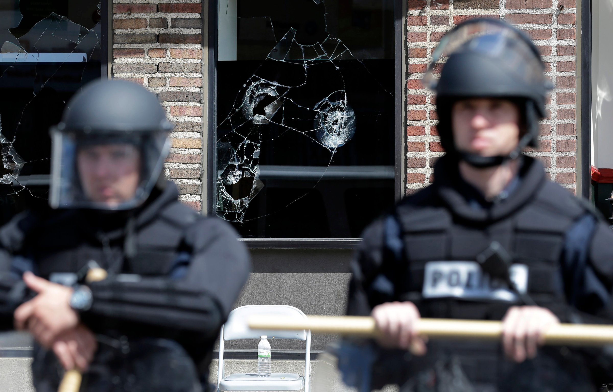 Broken store windows remain as members of the Anne Arundel County Police guard the intersection of North Avenue and Pennsylvania Avenue, on April 29, 2015, in Baltimore.