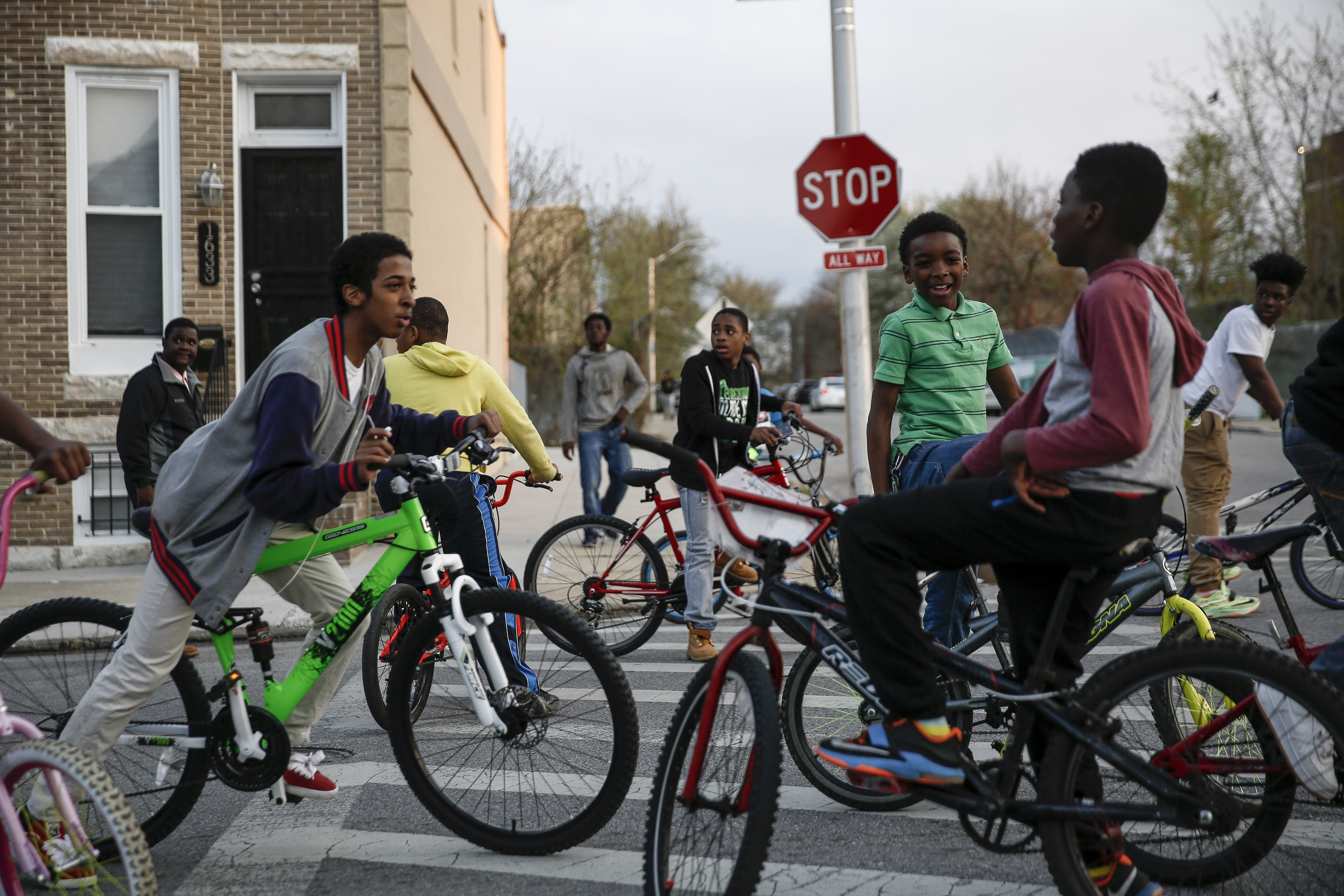 Children riding bikes look on as protesters march on Laurens Street in Baltimore on April 21, 2015.