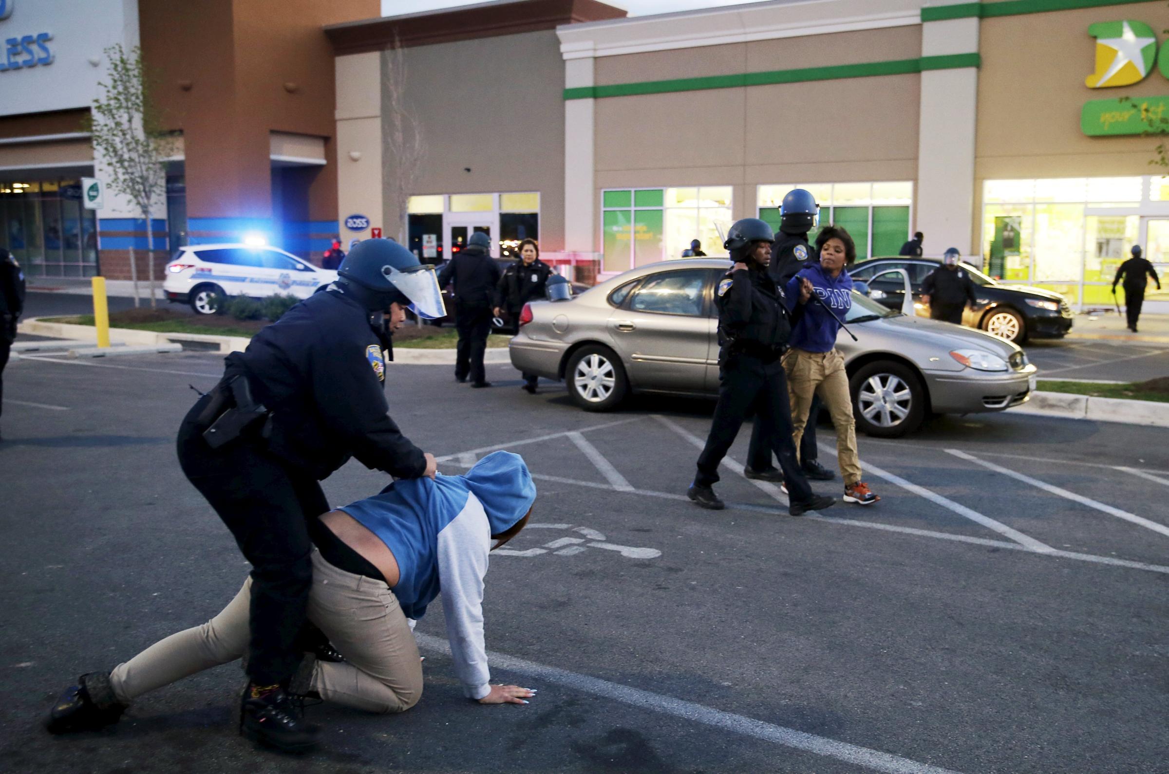 Baltimore police officers tackle and arrest looters after they emerged from a "Deals" store with merchandise during clashes between rioters and police in Baltimore