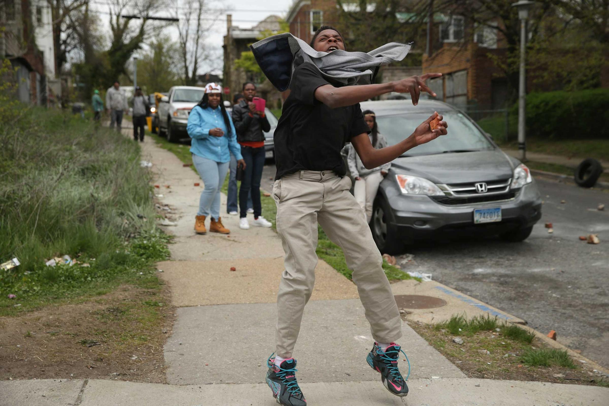 A man hurls a rock at Baltimore police officers outside the Mondawmin Mall following the funeral of Freddie Gray in Baltimore on April 27, 2015.