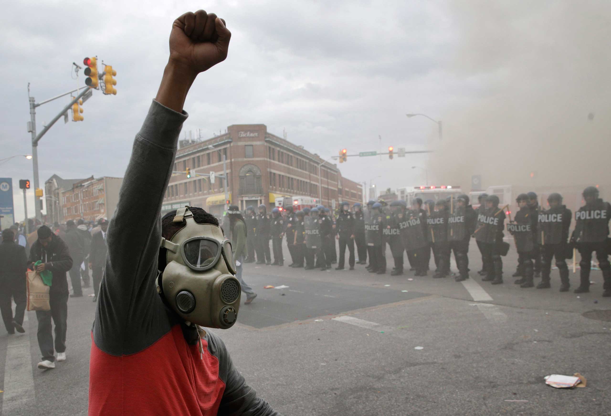 A demonstrator raises his fist as police stand in formation as a store burns during unrest following the funeral of Freddie Gray in Baltimore on Monday, April 27, 2015. (Patrick Semansky—AP)