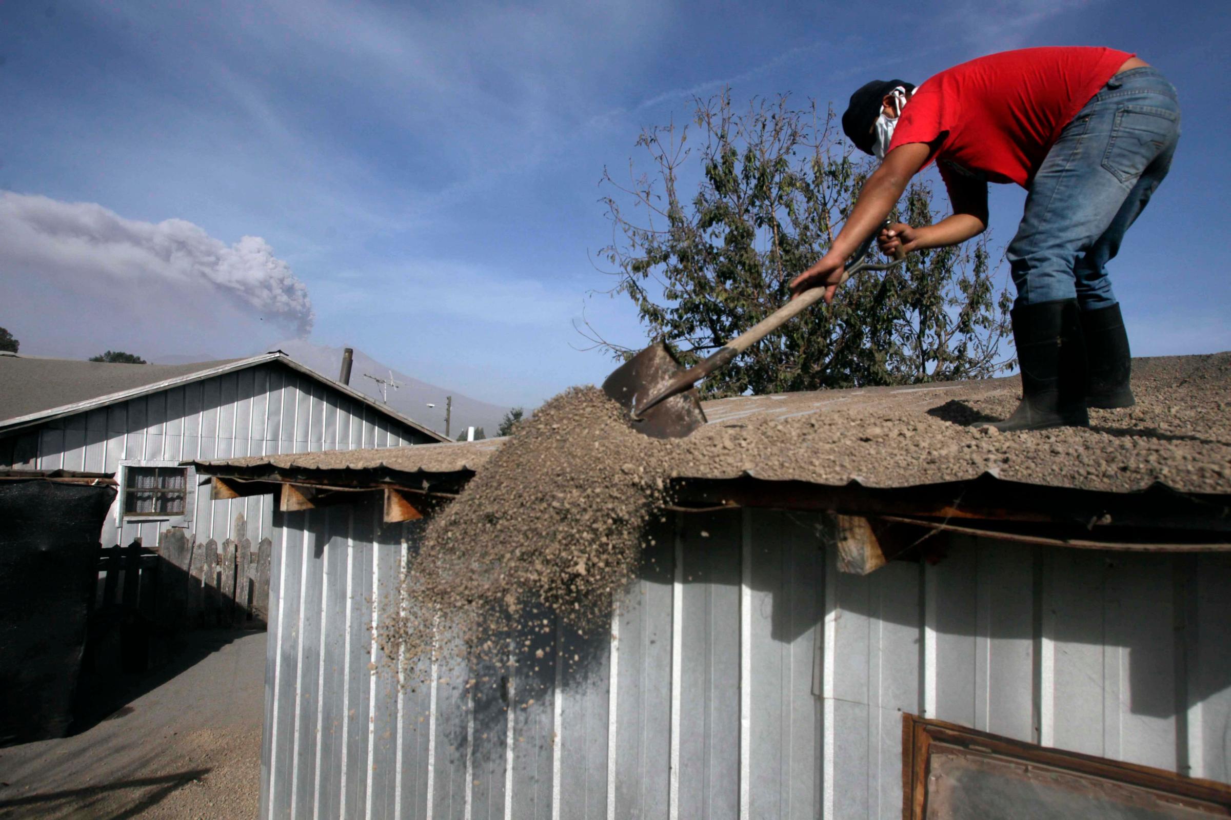 A man sweeps volcanic ash from the rooftop of his home in Puerto Varas, Chile