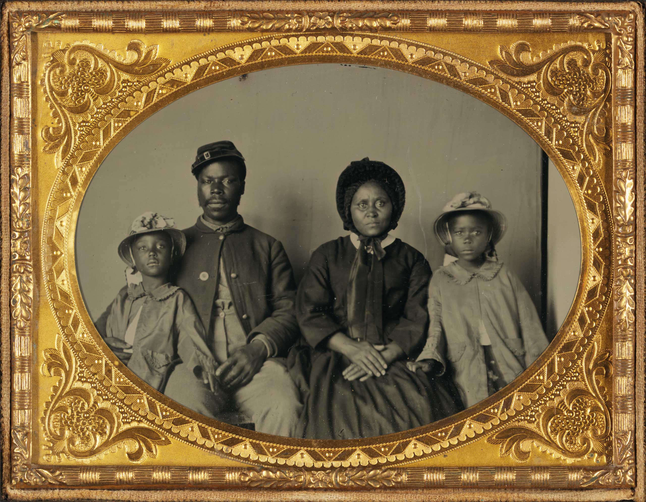 Unidentified African American soldier in Union uniform with wife and two daughters, 1863-1865.