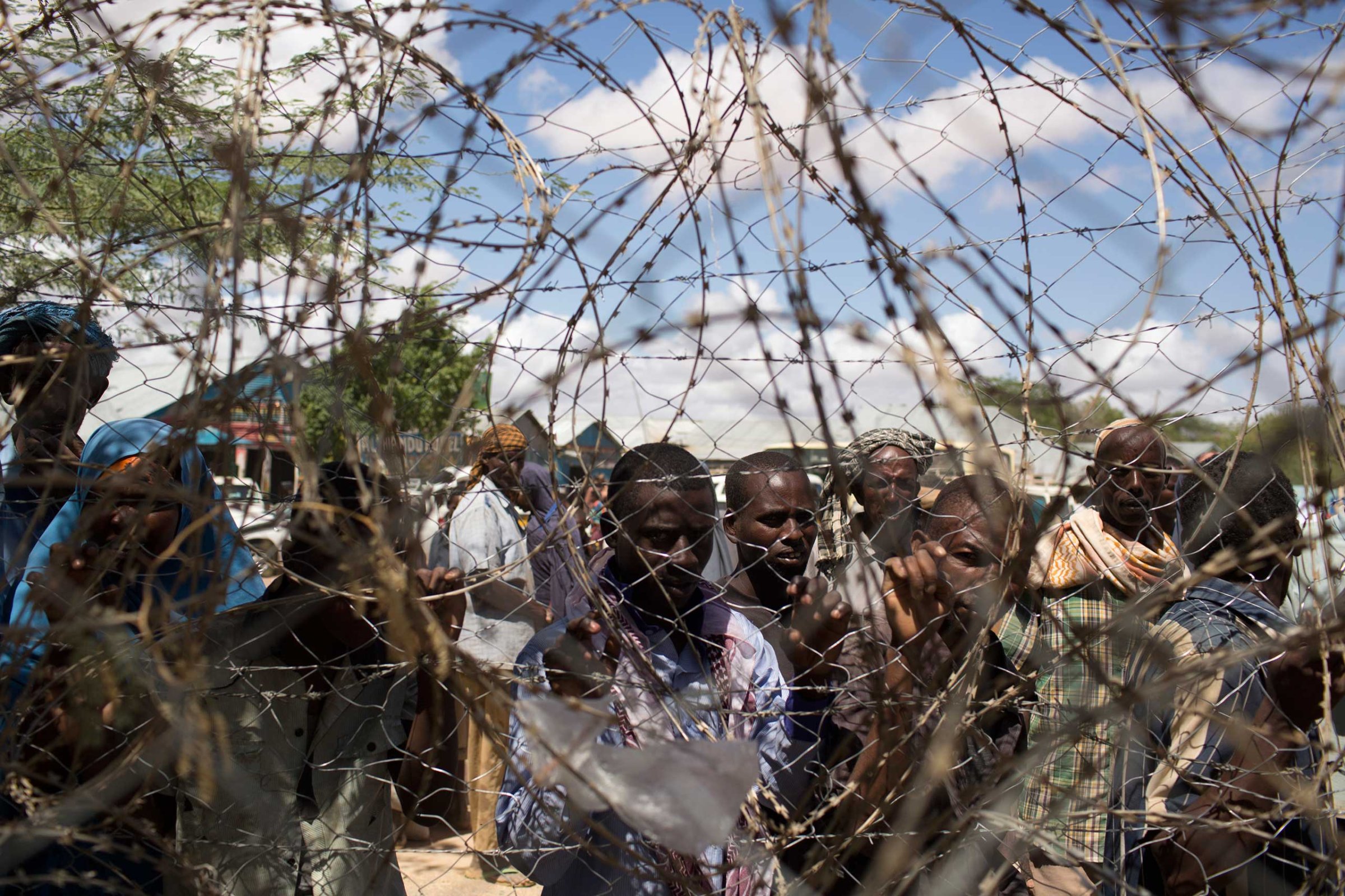 Somali refugees look through a barbwire fence in Dagahale, one of the several refugee settlements in Dadaab, Garissa County, northeastern Kenya in 2013.