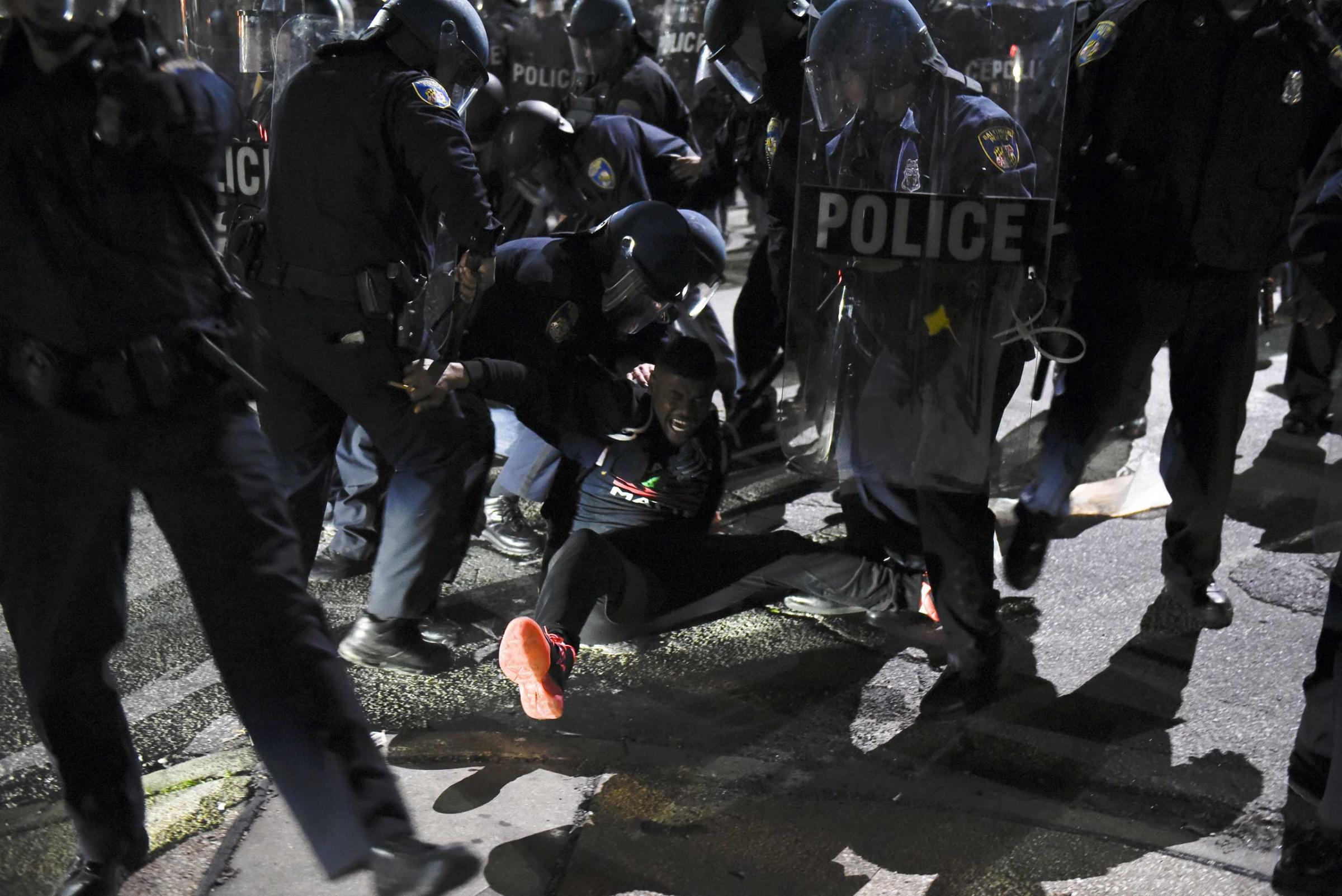 Law enforcement officers detain a demonstrator on Gilmore Avenue near Baltimore Police Department Western District during a protest against the death of Freddie Gray in police custody, in Baltimore on April 25, 2015.