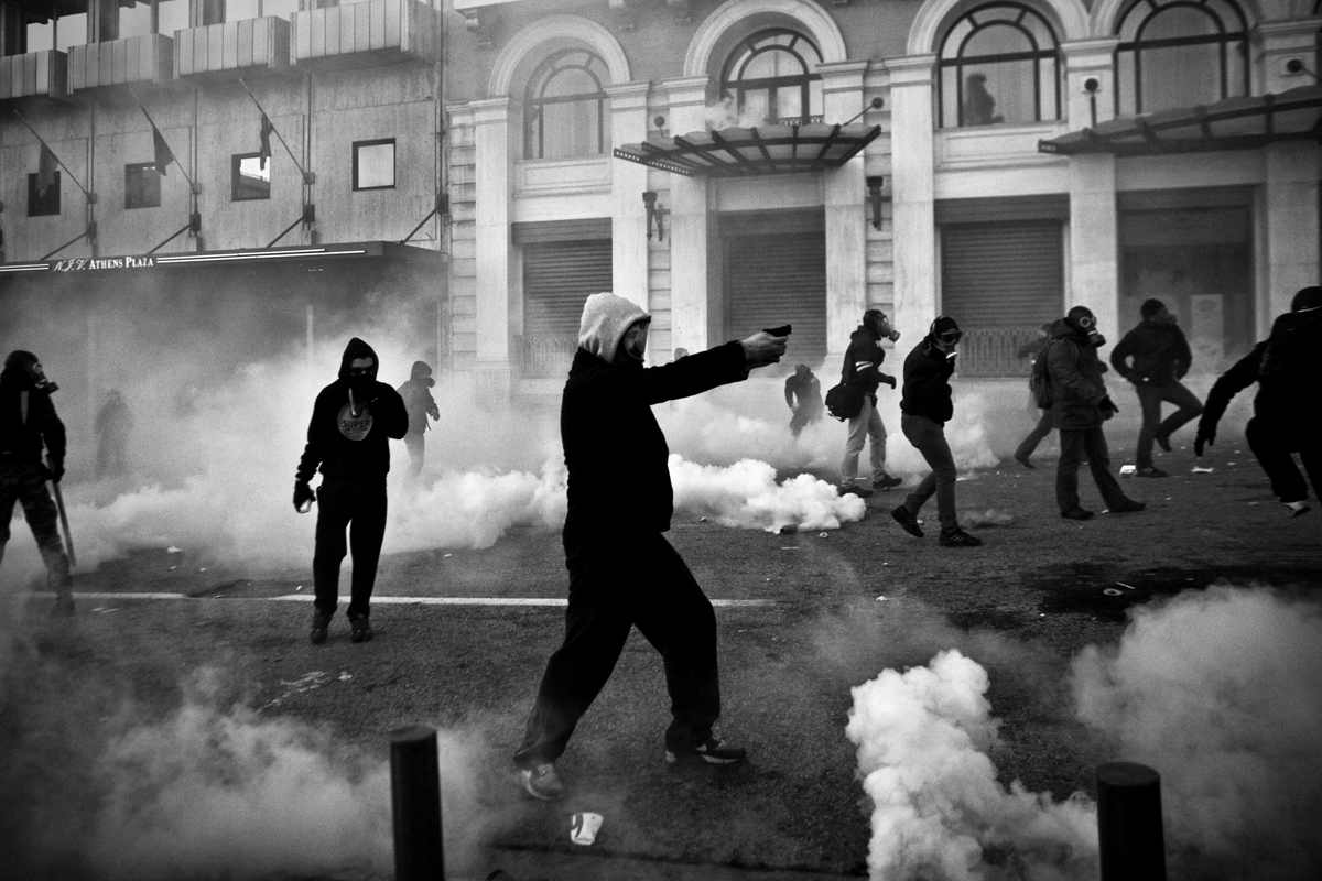 A protester uses a flare pistol against riot police during clashes during a general strike in Athens.