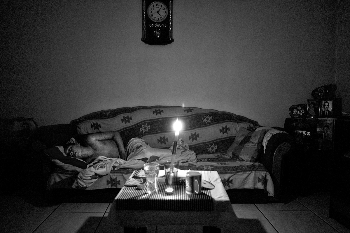 Dinos sleeps at the living room of his house with the light of a candle at the Perama district in Athens. Dinos lives with his mother Dimitra at a small house without electricity the last six months.  Thousands of Greek families live without electricity.