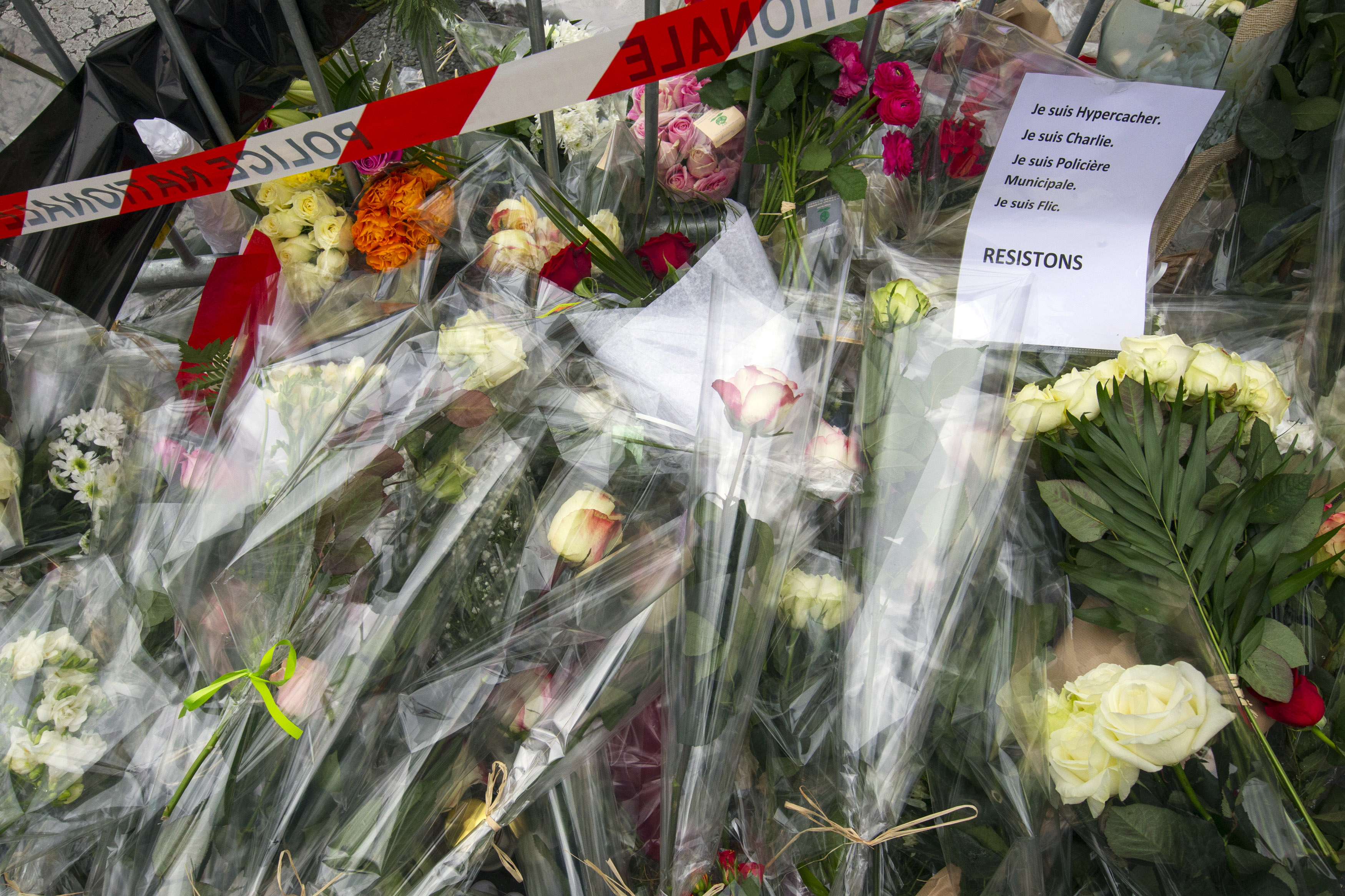 A sign reading "I am Hypercacher, I am Charlie and I am police officer, we must resist" is placed among flowers outside the Hyper Cacher kosher supermarket near Porte de Vincennes in eastern Paris