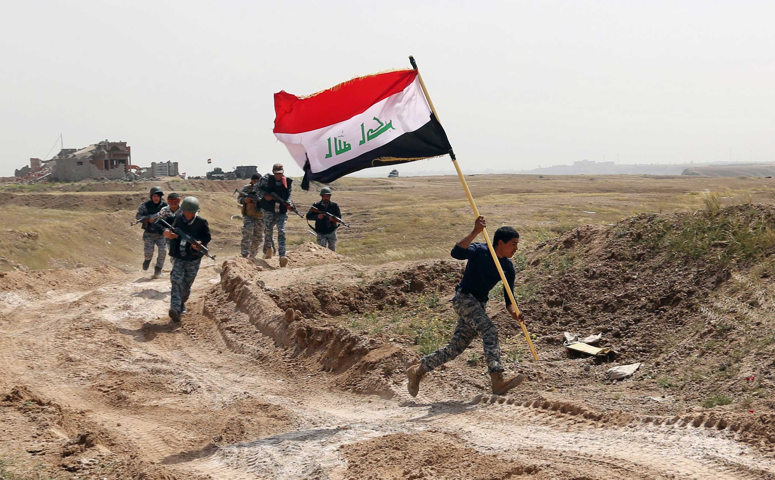 A member of the Iraqi security forces runs to plant the national flag as they surround Tikrit during clashes to regain the city from Islamic State militants, 80 miles north of Baghdad, Iraq, March 30, 2015.