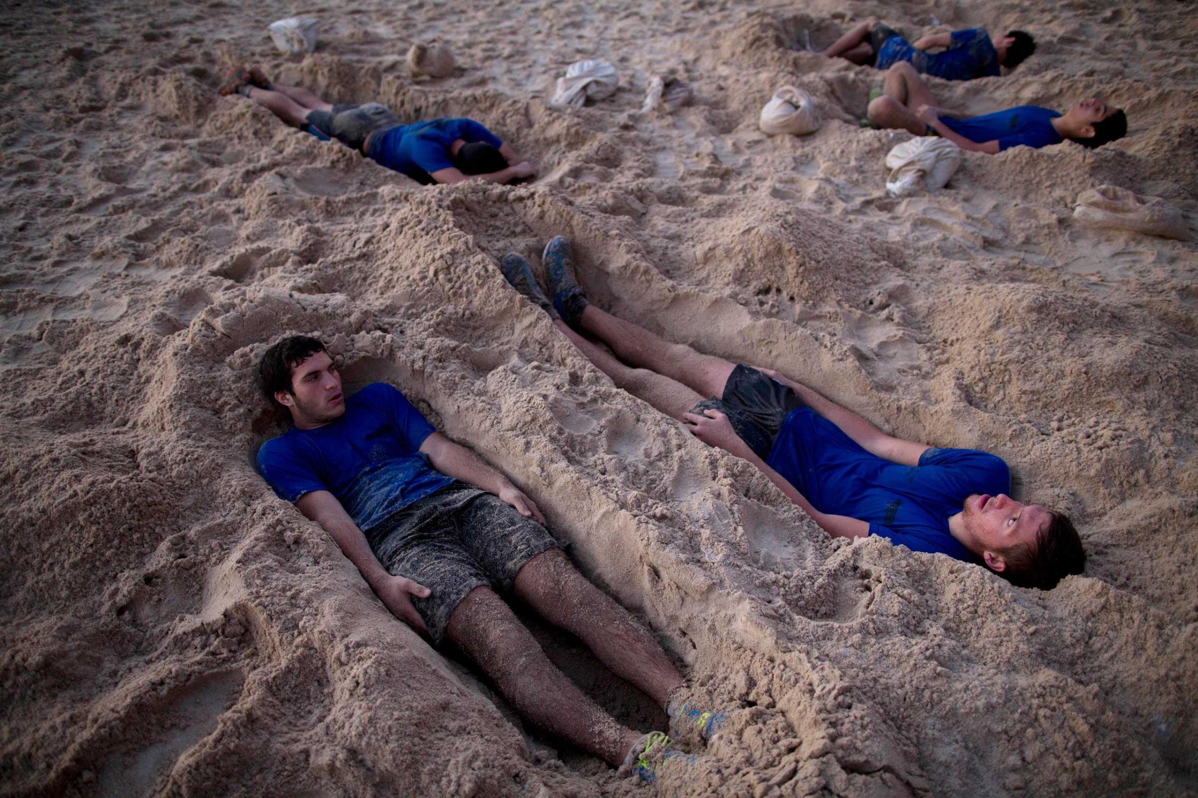 High-school seniors preparing to join the Israeli military later this year lie in foxholes during training in Shefayim, central Israel, March 5, 2015.