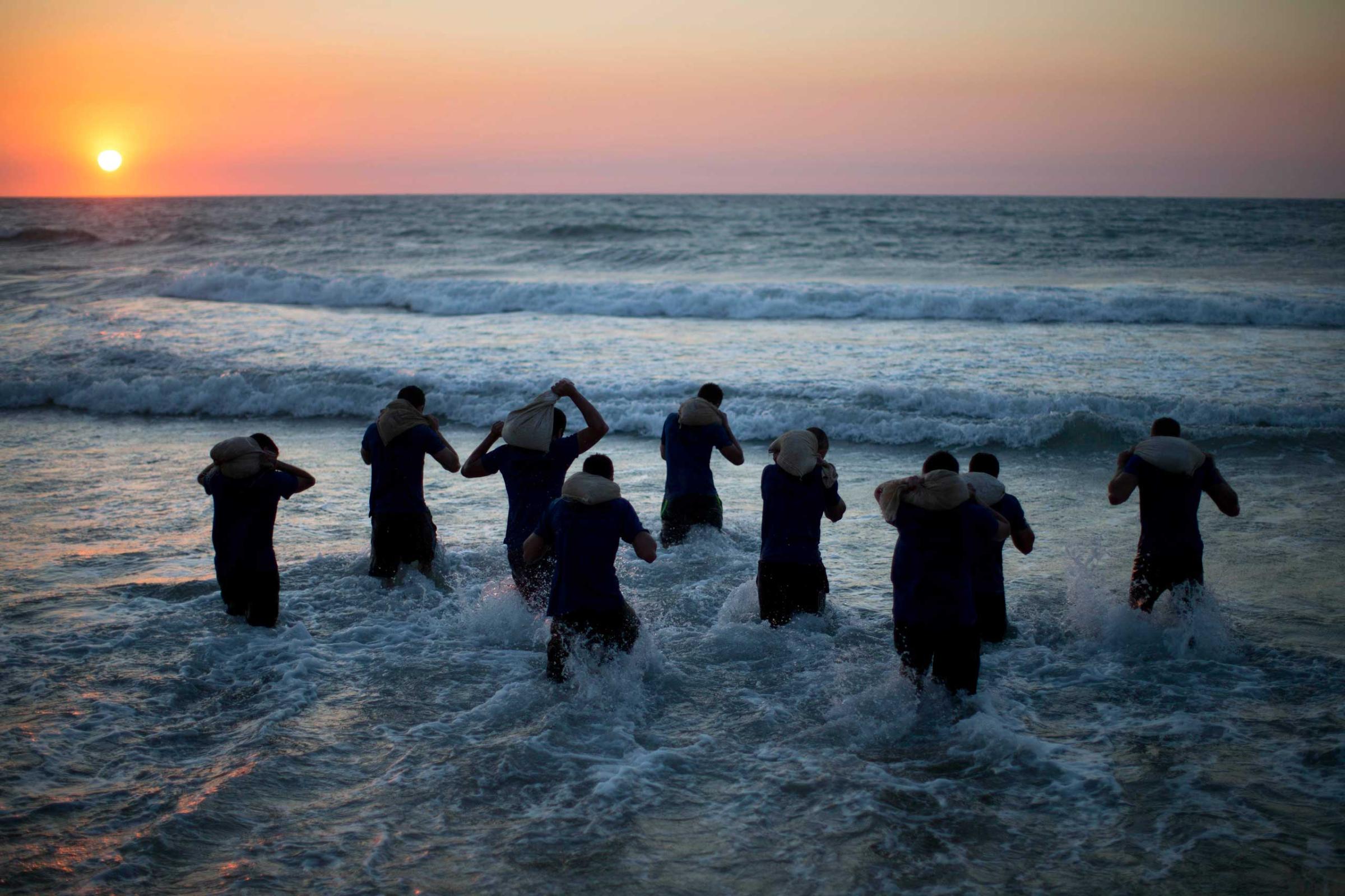 High-school seniors walk into the sea carrying weighted bags the during military combat fitness training in Shefayim, central Israel, March 5, 2015.