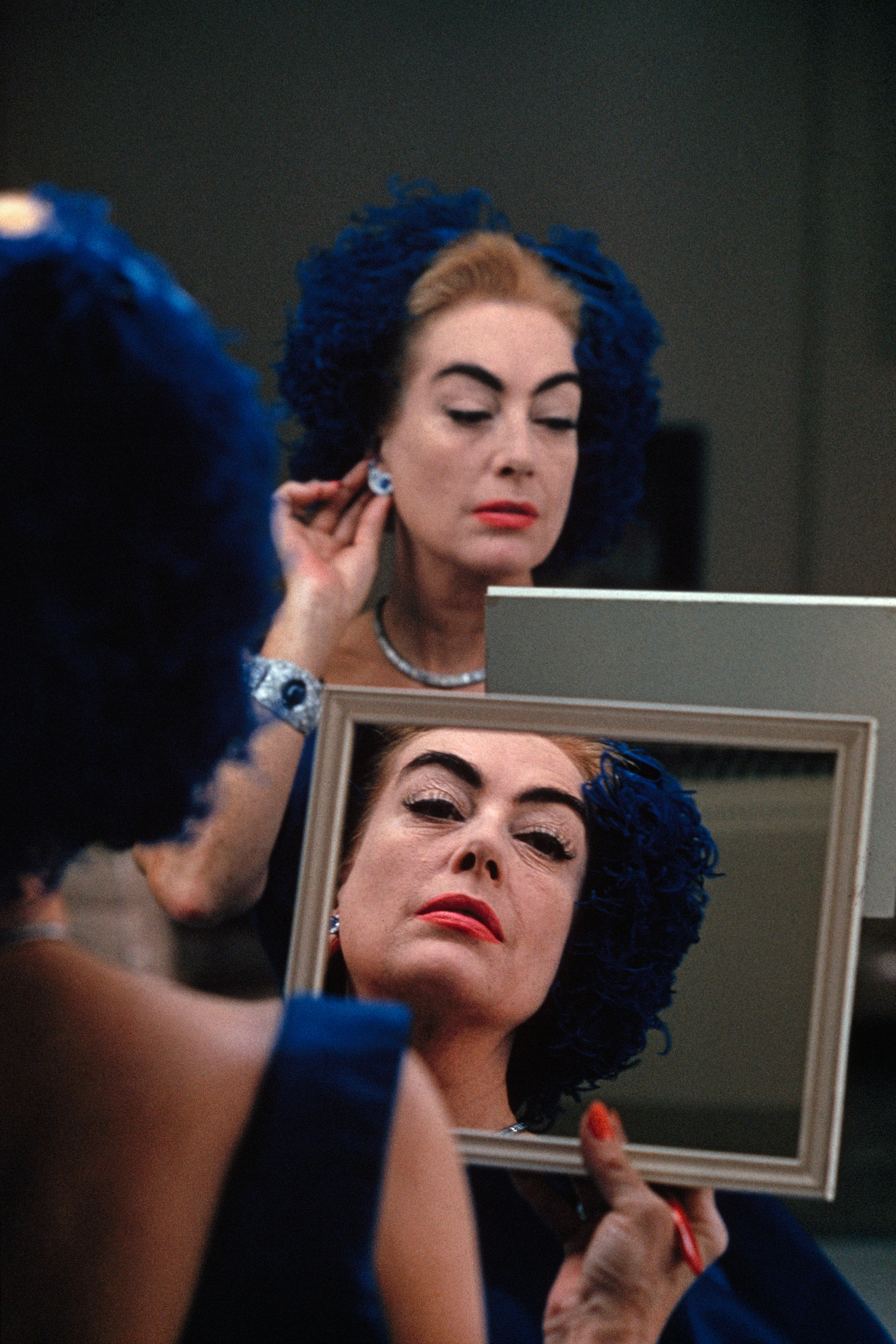Joan Crawford checking her makeup, Hollywood, 1959.