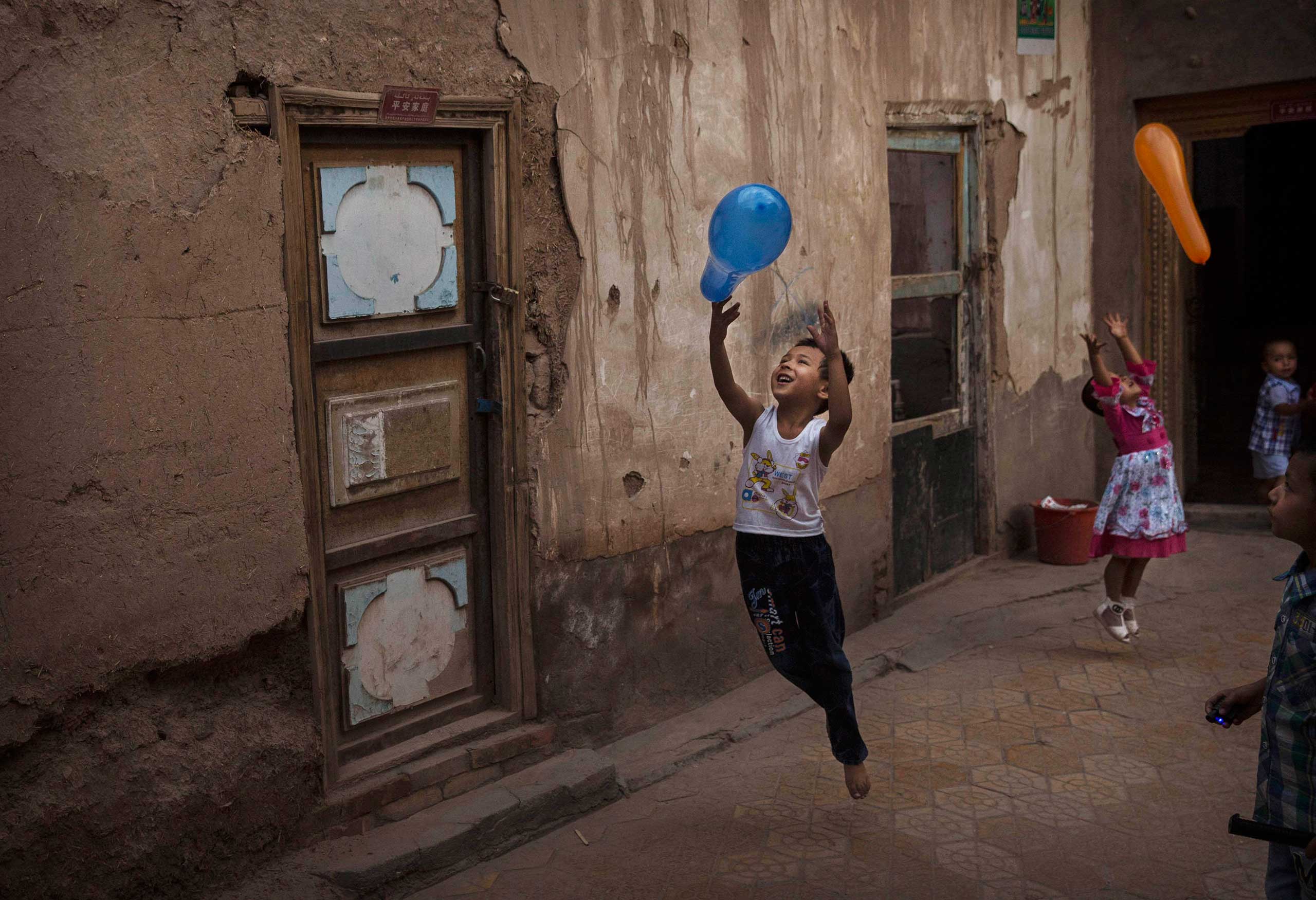 Uighur children play with balloons on the Eid holiday in alleyway in old Kashgar, Xinjiang Province, China, July 29, 2014.