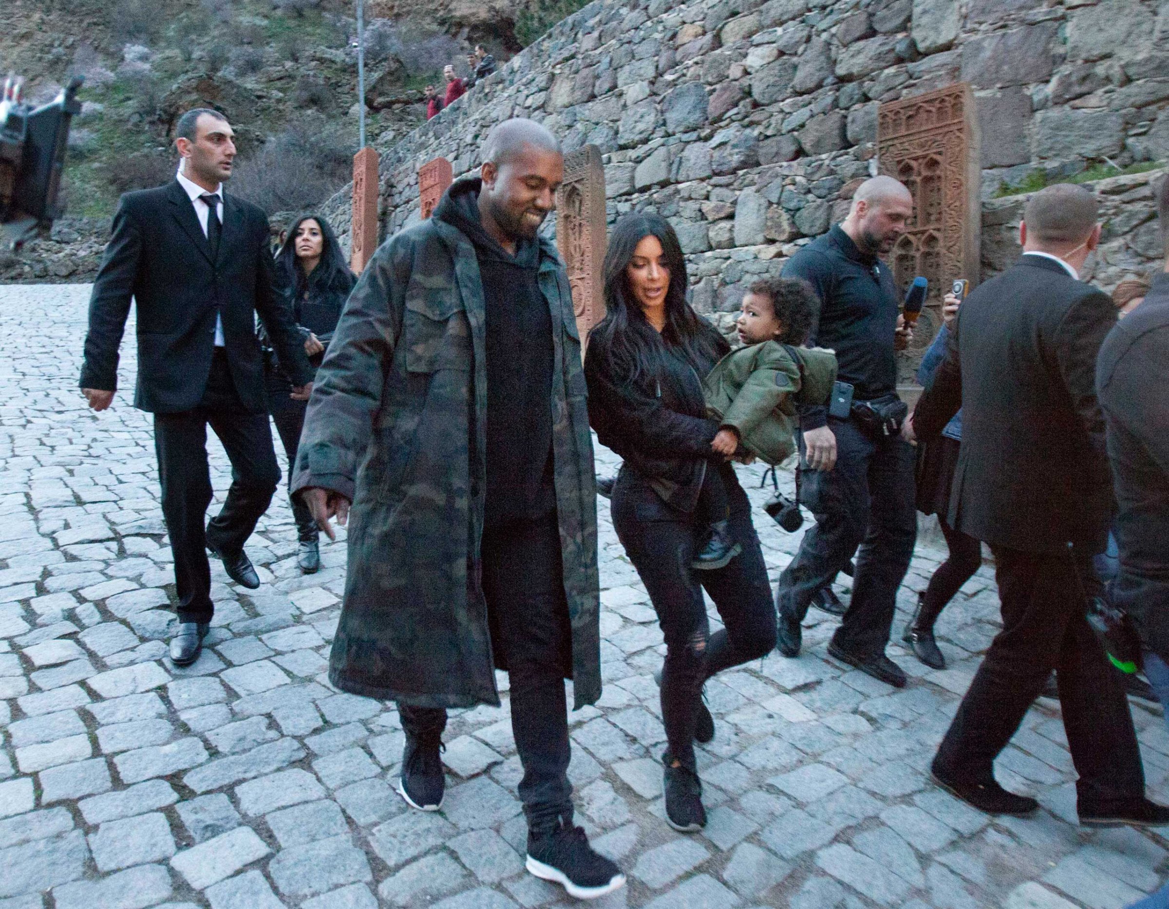 U.S. TV personality Kim Kardashian, center, carriers daughter North as she walks alongside her husband Kanye West visit the Geghard Monastery near Goght, Armenia, April 9, 2015.