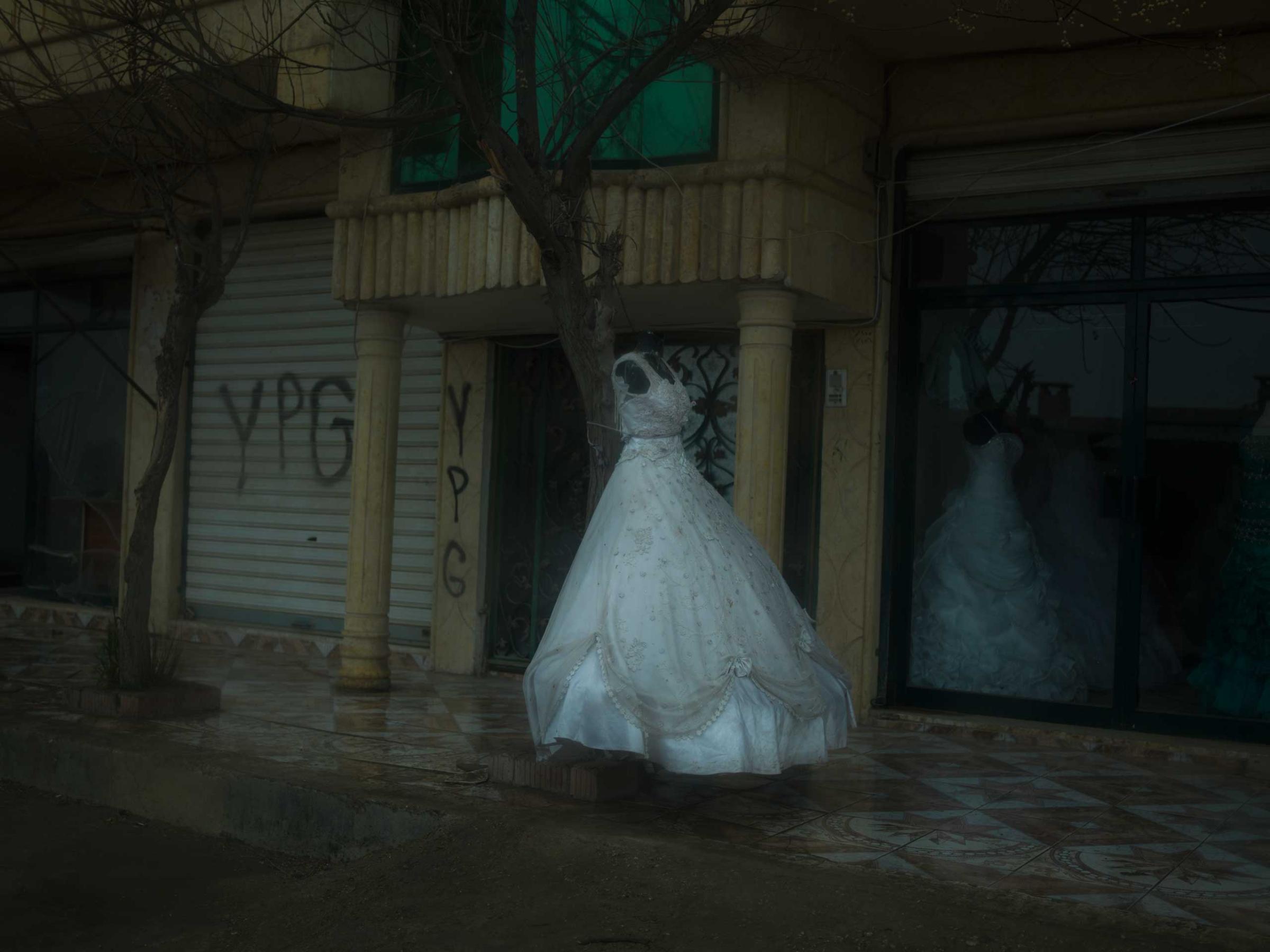 A wedding dress outside a bridal shop in a town near Qamishlou, Syria. YPG graffiti can be seen on the walls of adjacent buildings. YPJ and YPG members are neither allowed to marry, nor can they have sexual relationships, according the their ideology. Newsha Tavakolian for TIME