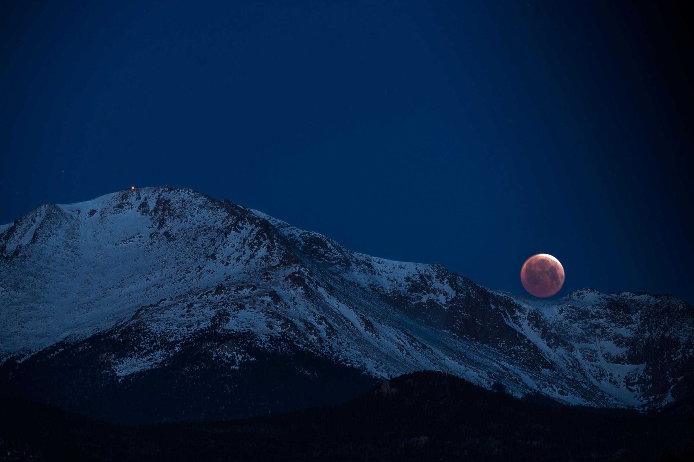 The blood moon lunar eclipse sets behind Pikes Peak April 4, 2015 in Colorado Springs.