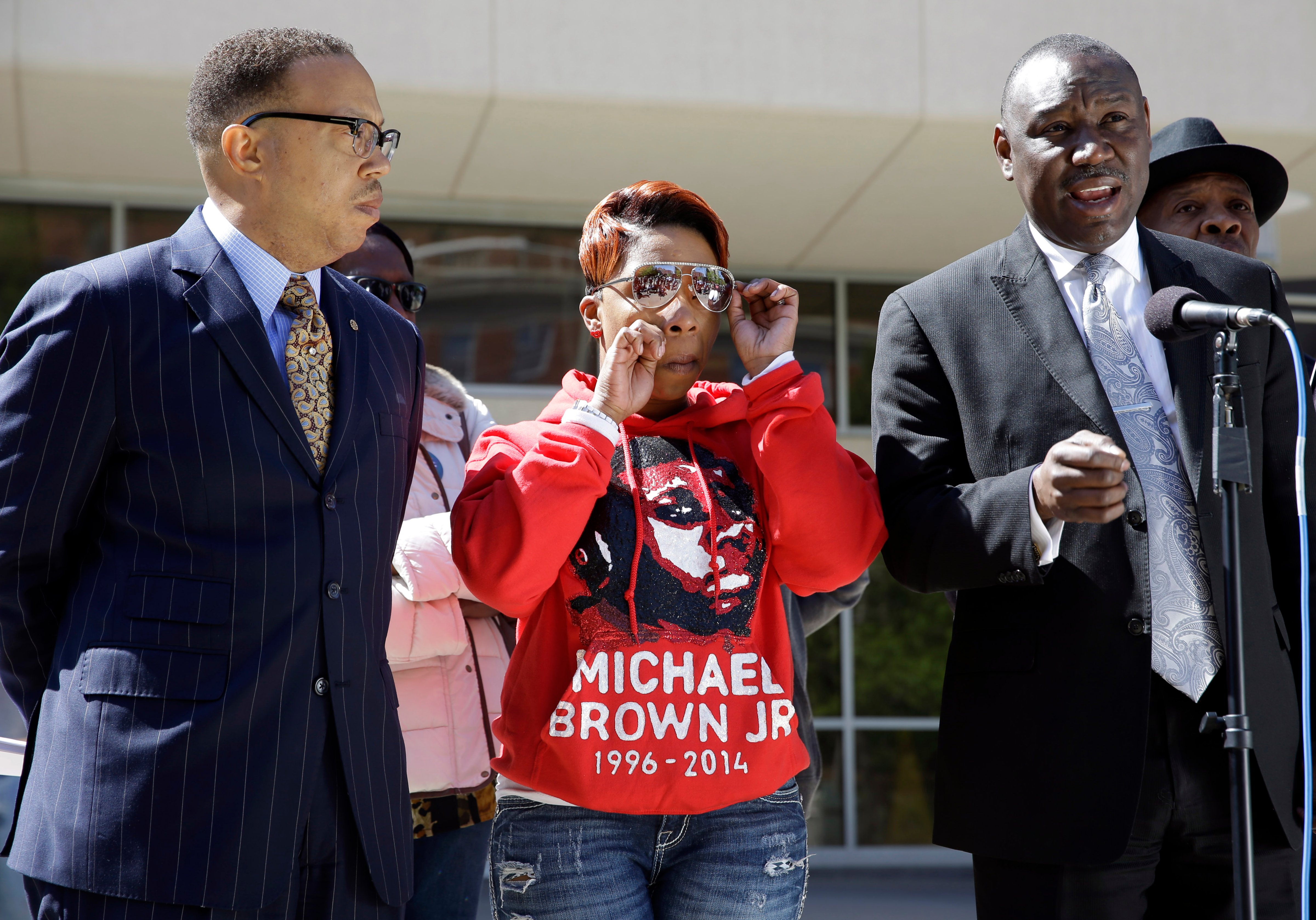 Lesley McSpadden, mother of Michael Brown, wipes her eye as she is flanked by her attorneys Anthony D. Gray, left, and Benjamin L. Crump, right, during a news conference April 23, 2015, in Clayton, Mo. (Jeff Roberson—AP)