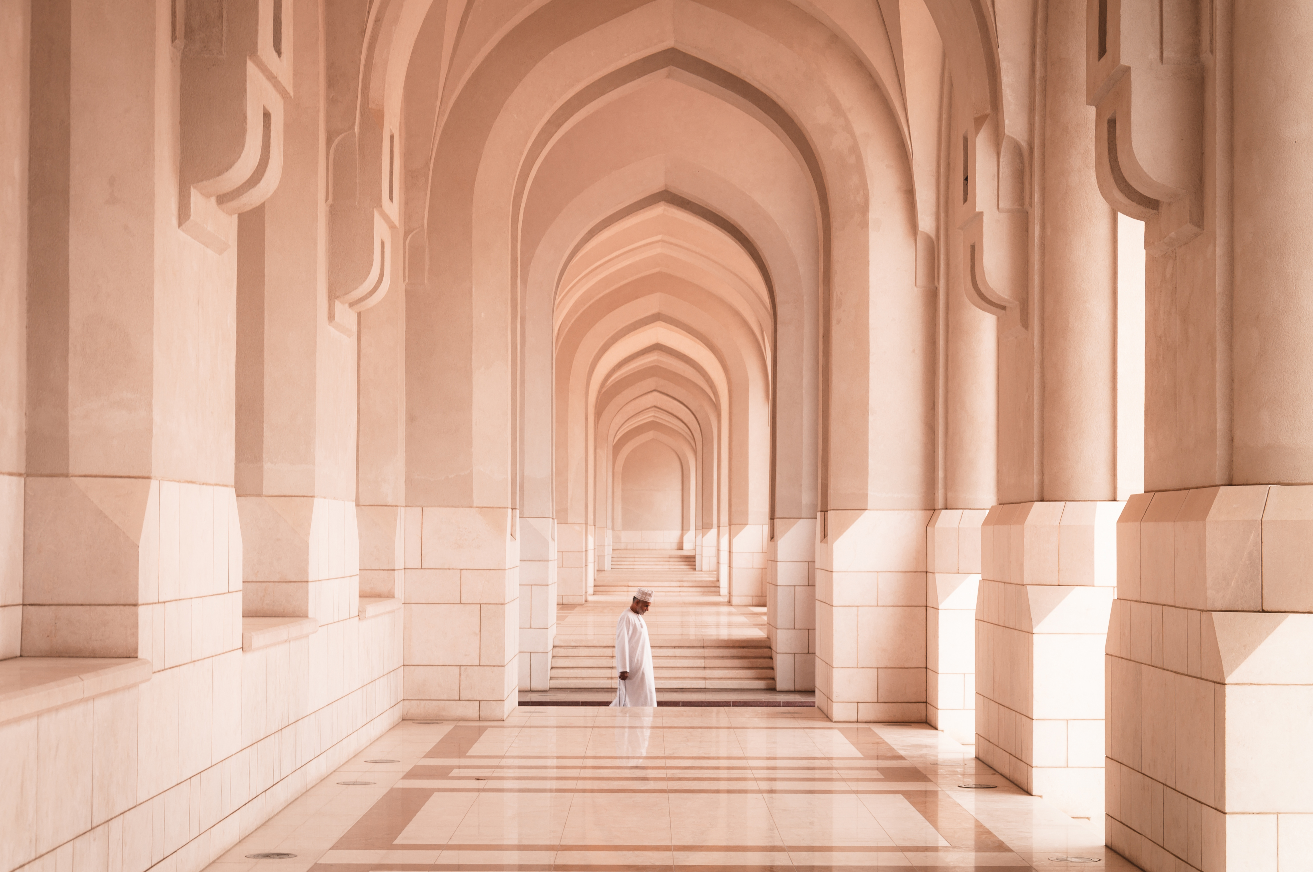 Man passing through arches of colonnade, Oman