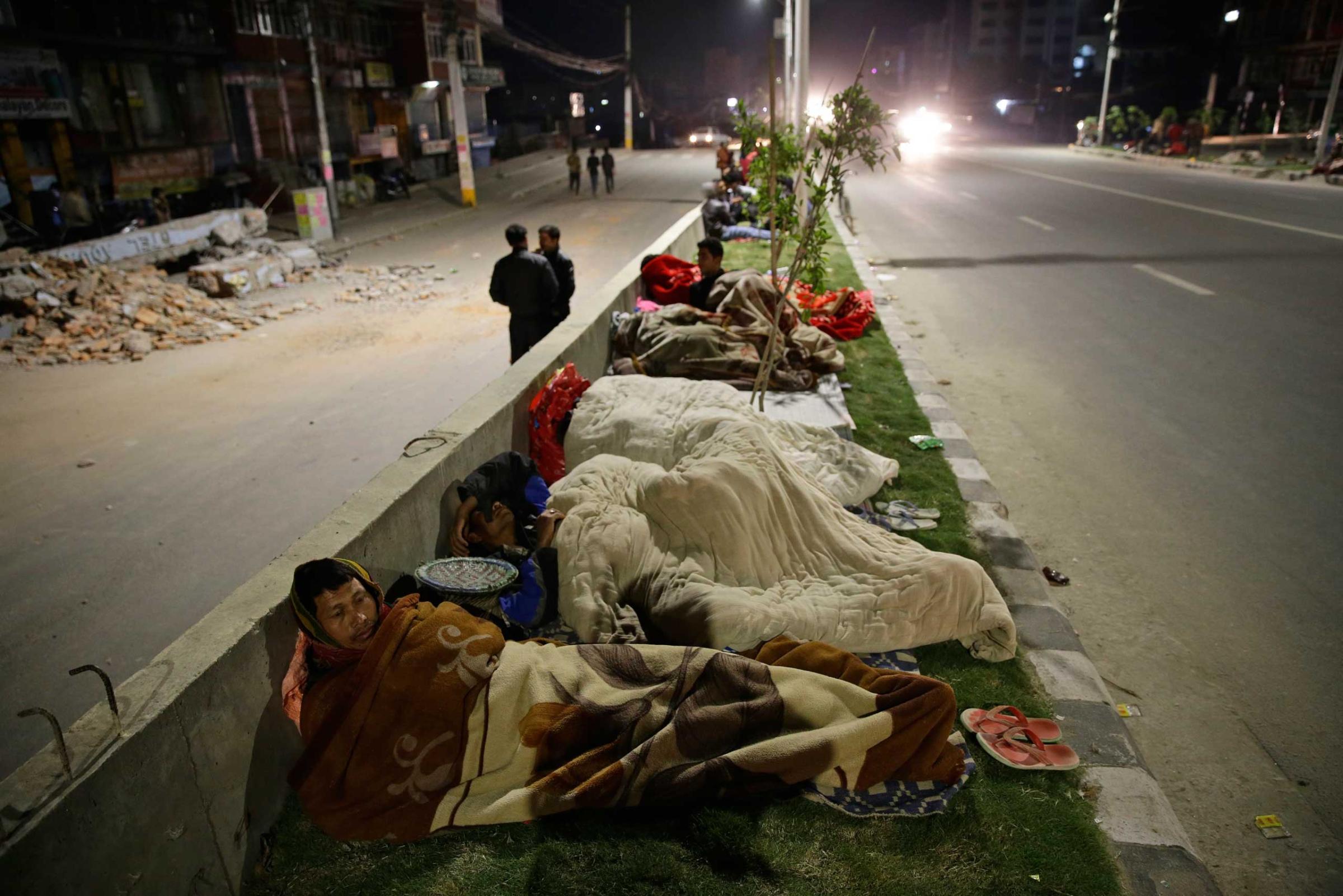 People sleep outside on a street following a massive earthquake in Kathmandu on April on 2015.