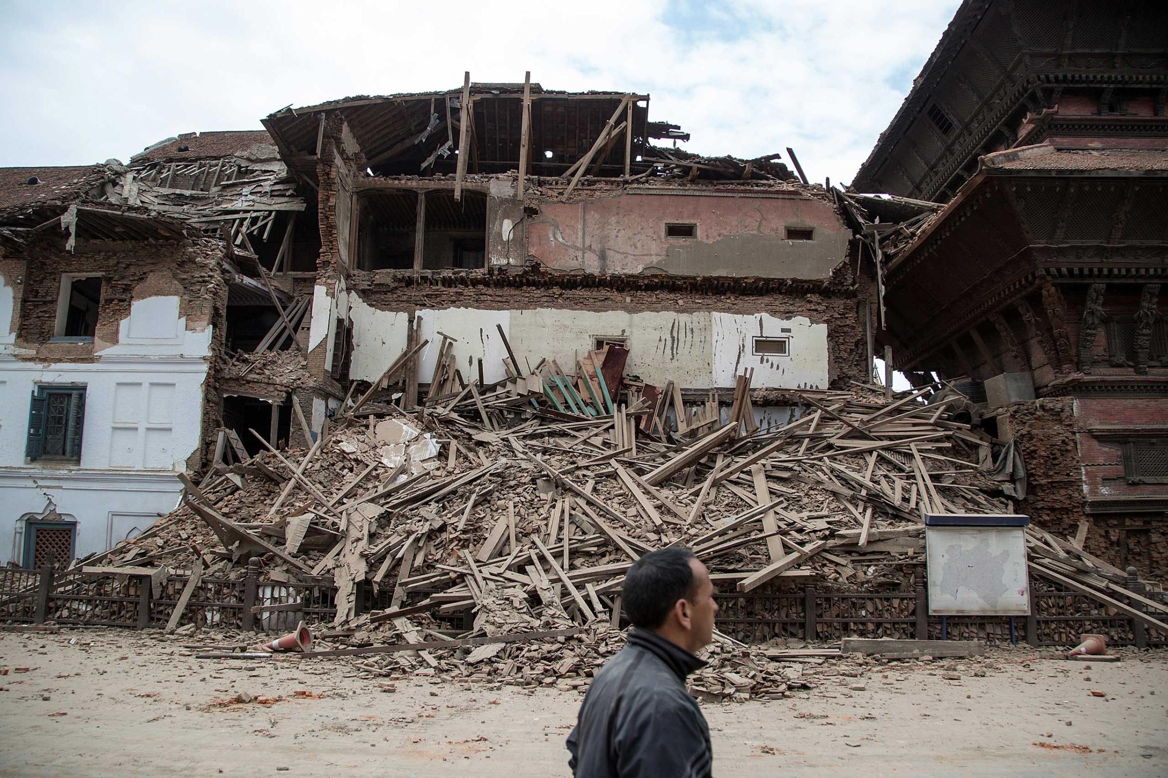 Resident passes in front of a collapsed temple at Basantapur Durbar Square in Kathmandu on April 25, 2015.