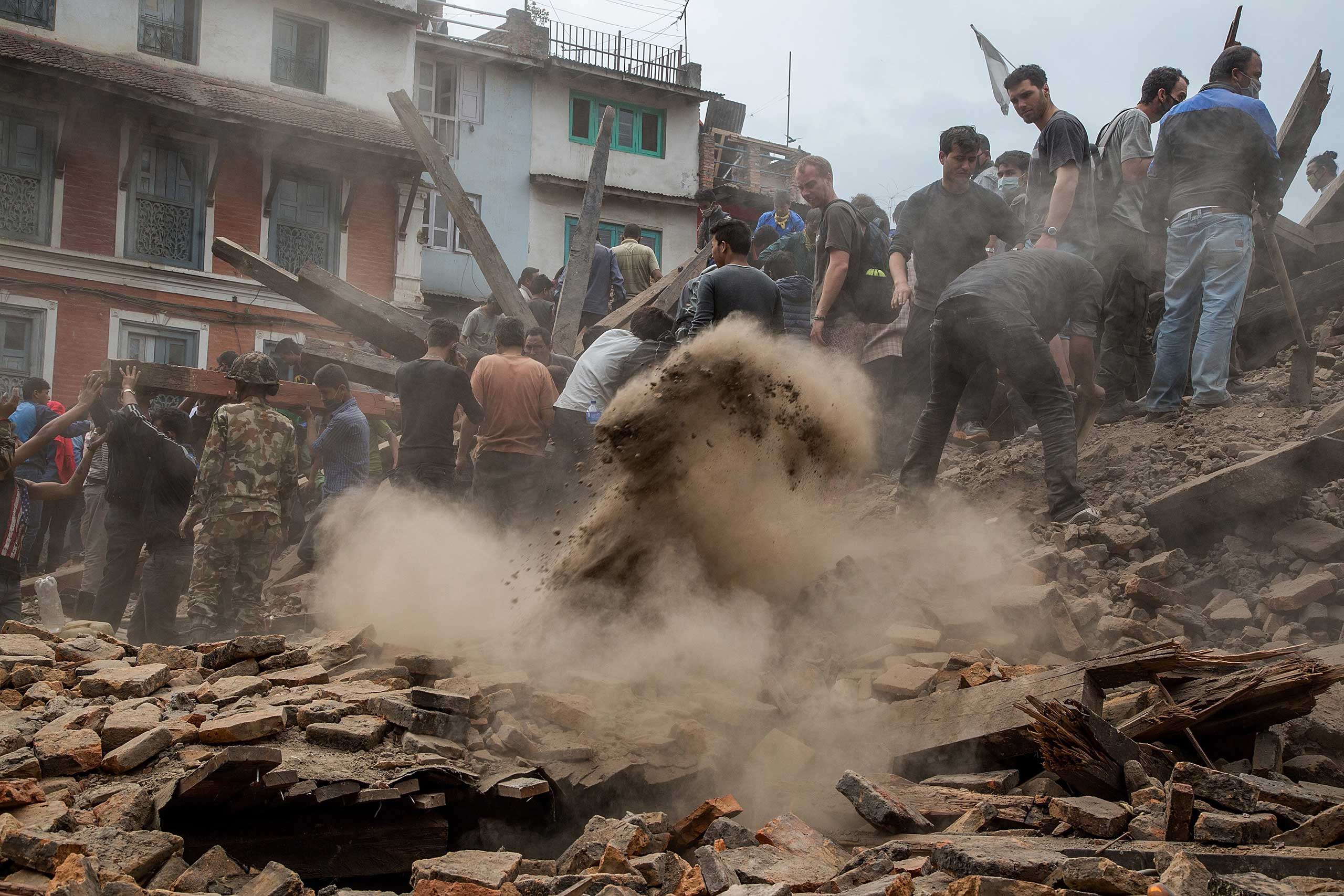 Emergency workers and bystanders clear debris while searching for survivors under a collapsed temple in Basantapur Durbar Square following an earthquake in Kathmandu on April 25, 2015.