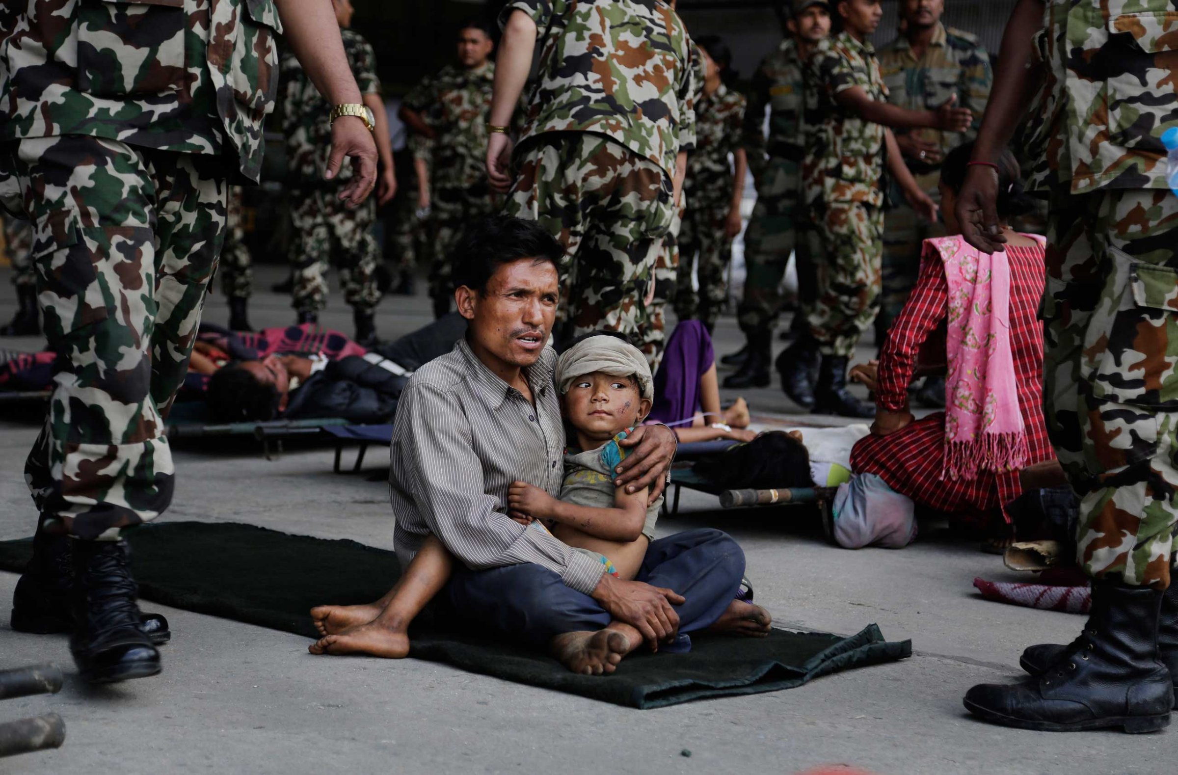 A man sits with a child on his lap as victims of Saturday's earthquake wait for ambulances after being evacuated at the airport in Kathmandu, Nepal, on April 27, 2015.