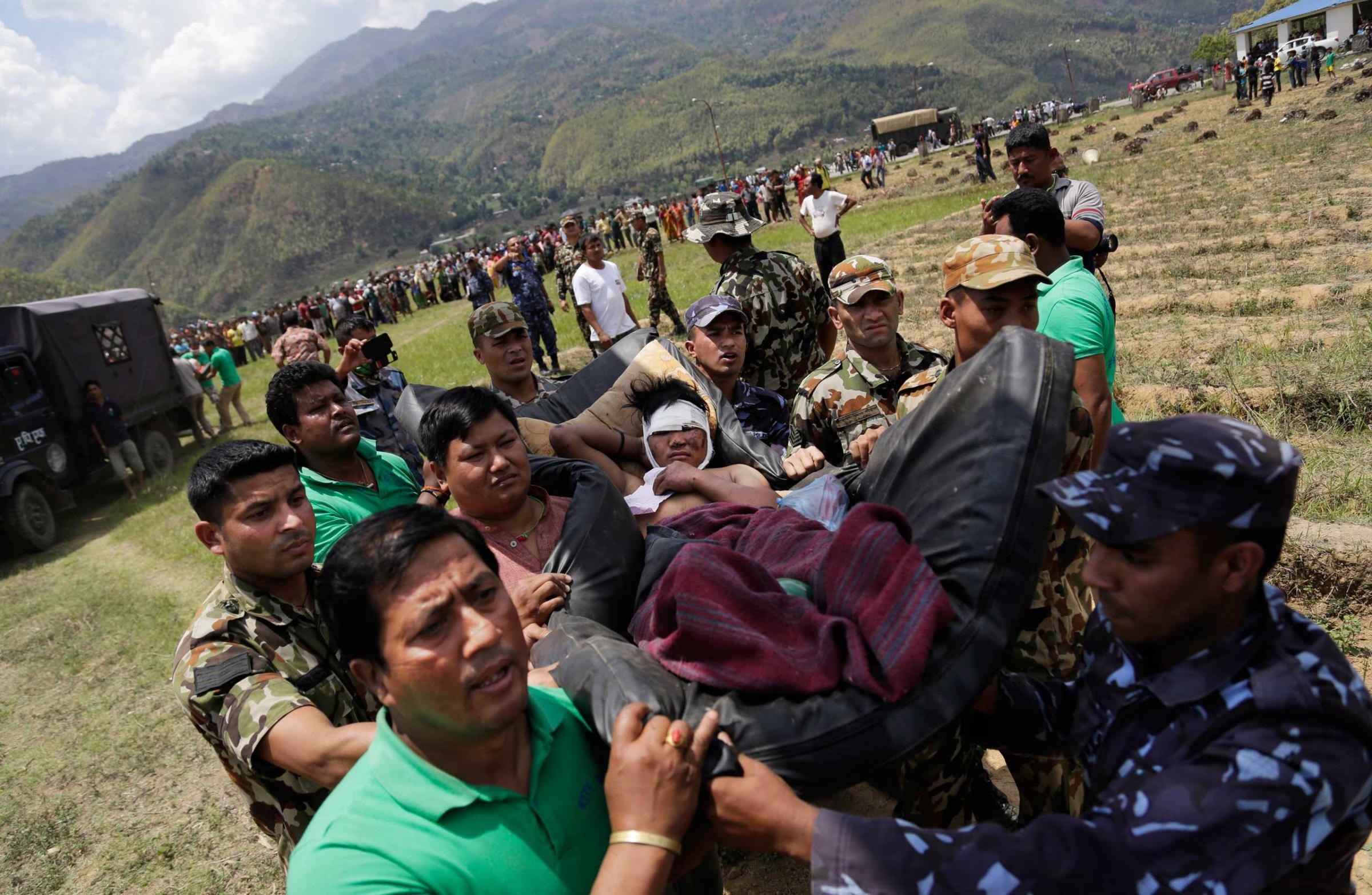 Nepalese soldiers carry a wounded man on a makeshift stretcher to an Indian Air Force helicopter as they evacuate victims of Saturday's earthquake from Trishuli Bazar to Kathmandu airport in Nepal on April 27, 2015.