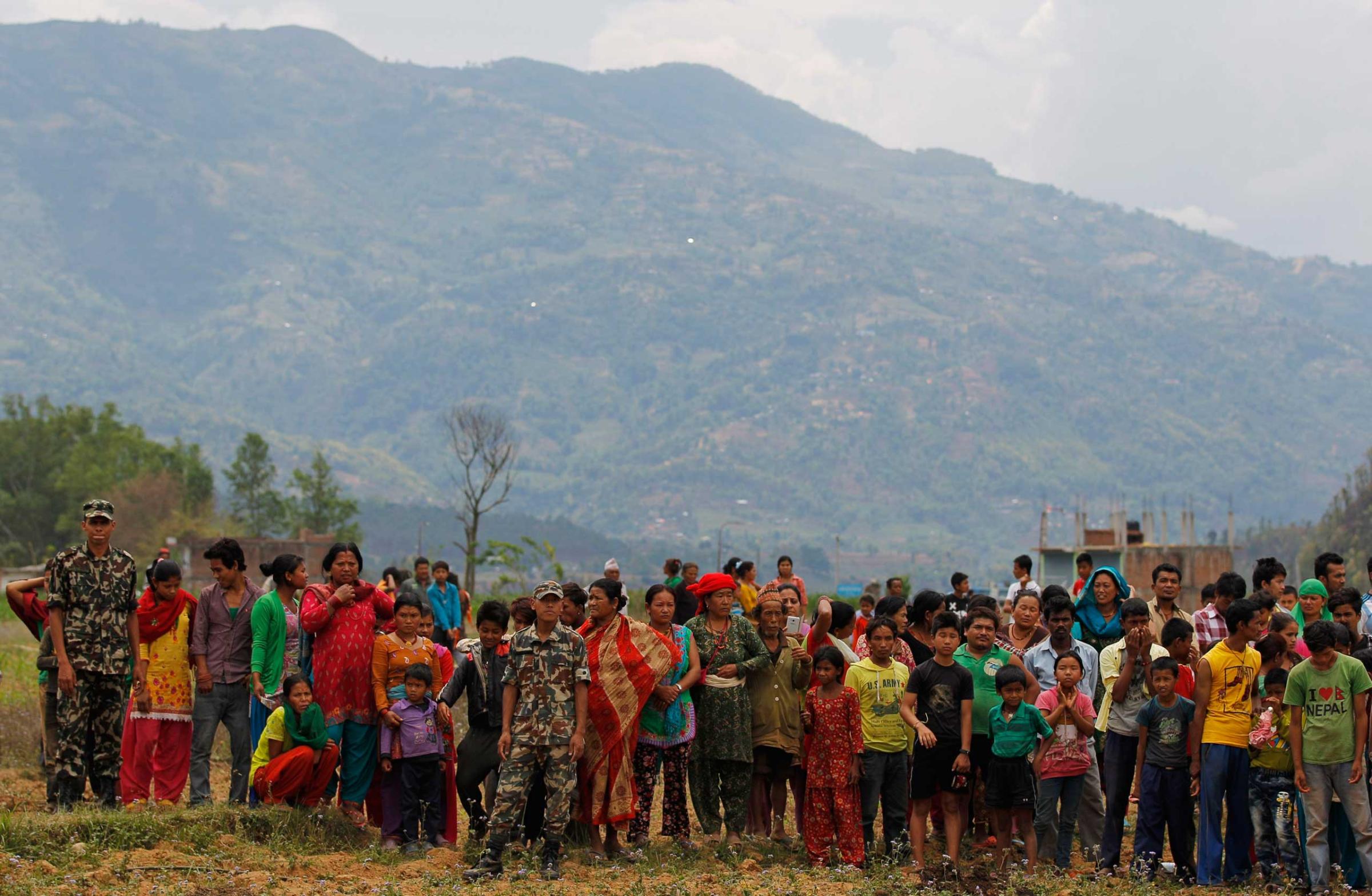 Nepalese villagers watch as relief material is brought in an Indian air force helicopter for victims of Saturdayís earthquake at Trishuli Bazar in Nepal on April 27, 2015.