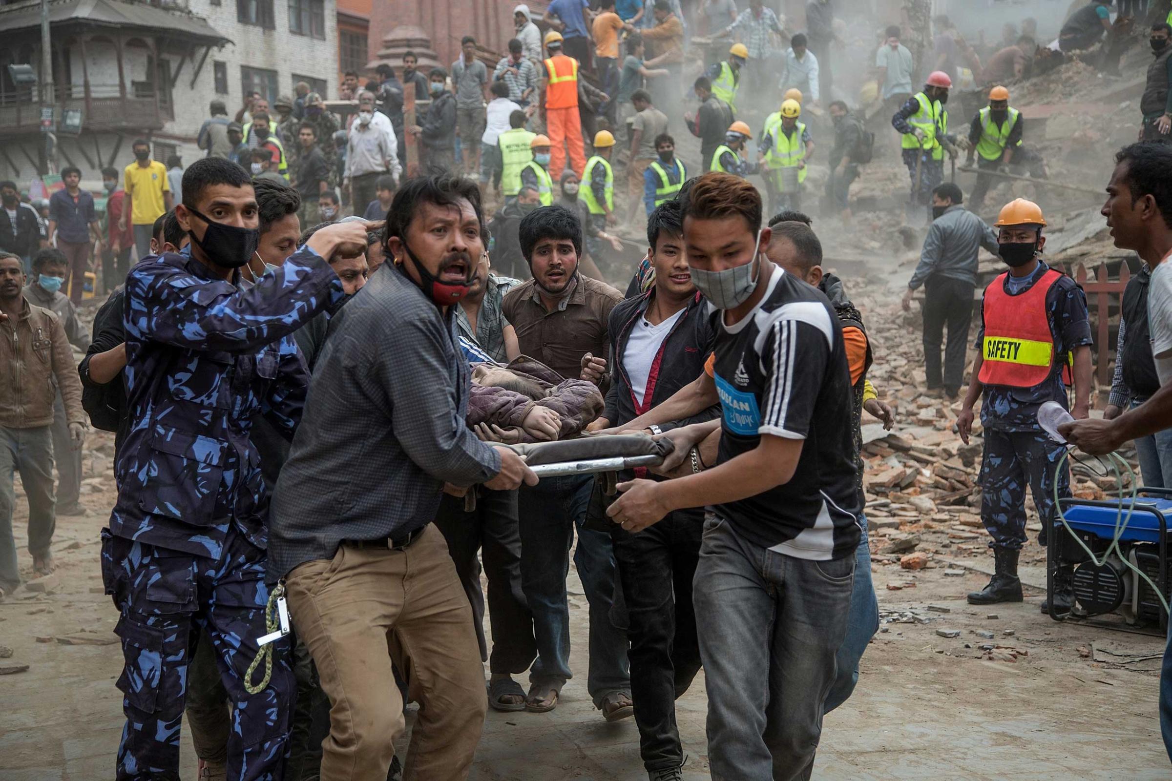People carry a victim who was removed from the collapsed Dharara tower following the earthquake in Kathmandu.