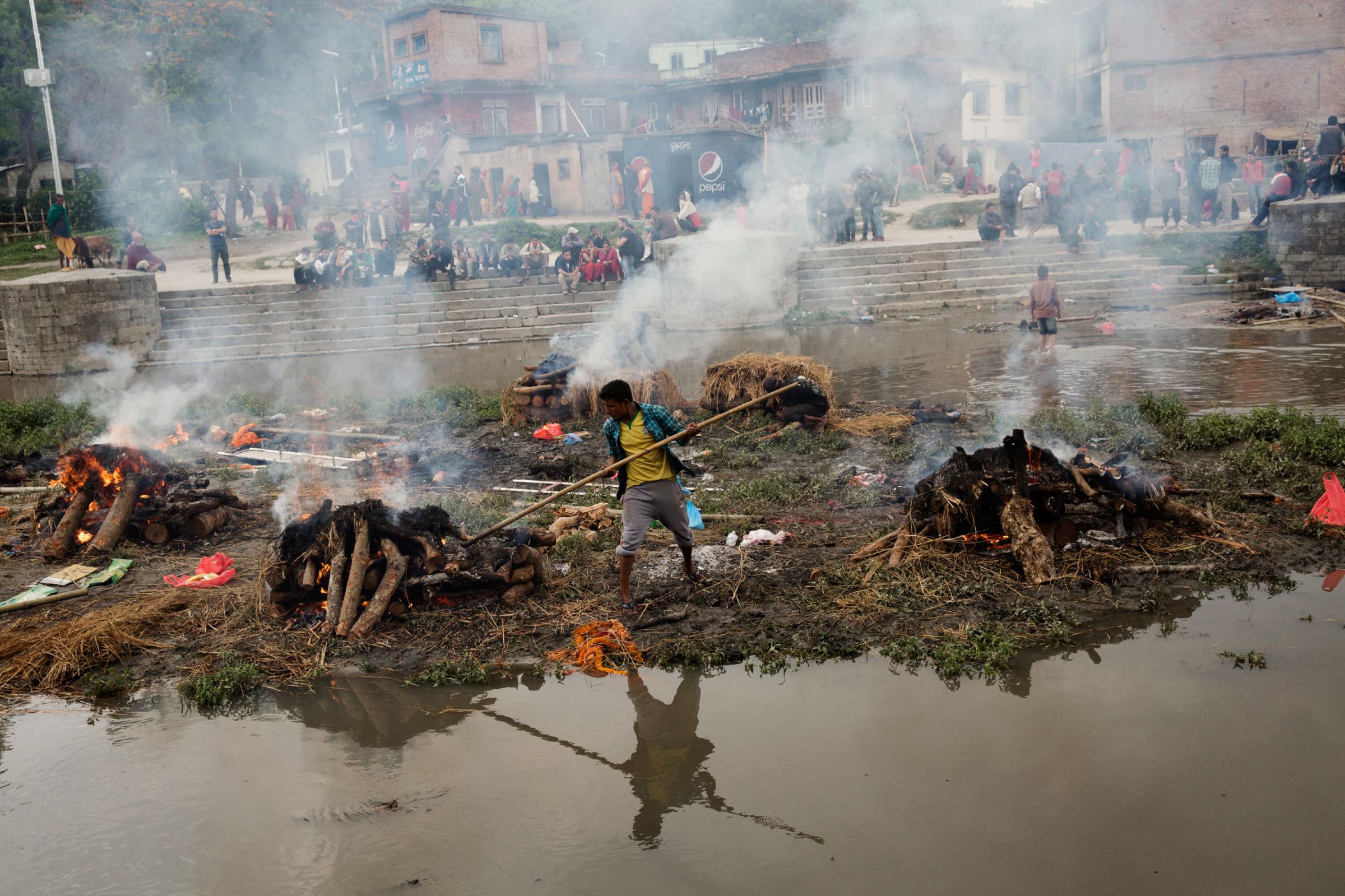 A Hindu Nepali man tends to a funeral pyre built for a person killed in the earthquake in Nepal, on the river in Kathmandu, Nepal on April. 27, 2015. Nepal had a severe earthquake on April 25th. Photo by Adam Ferguson for Time