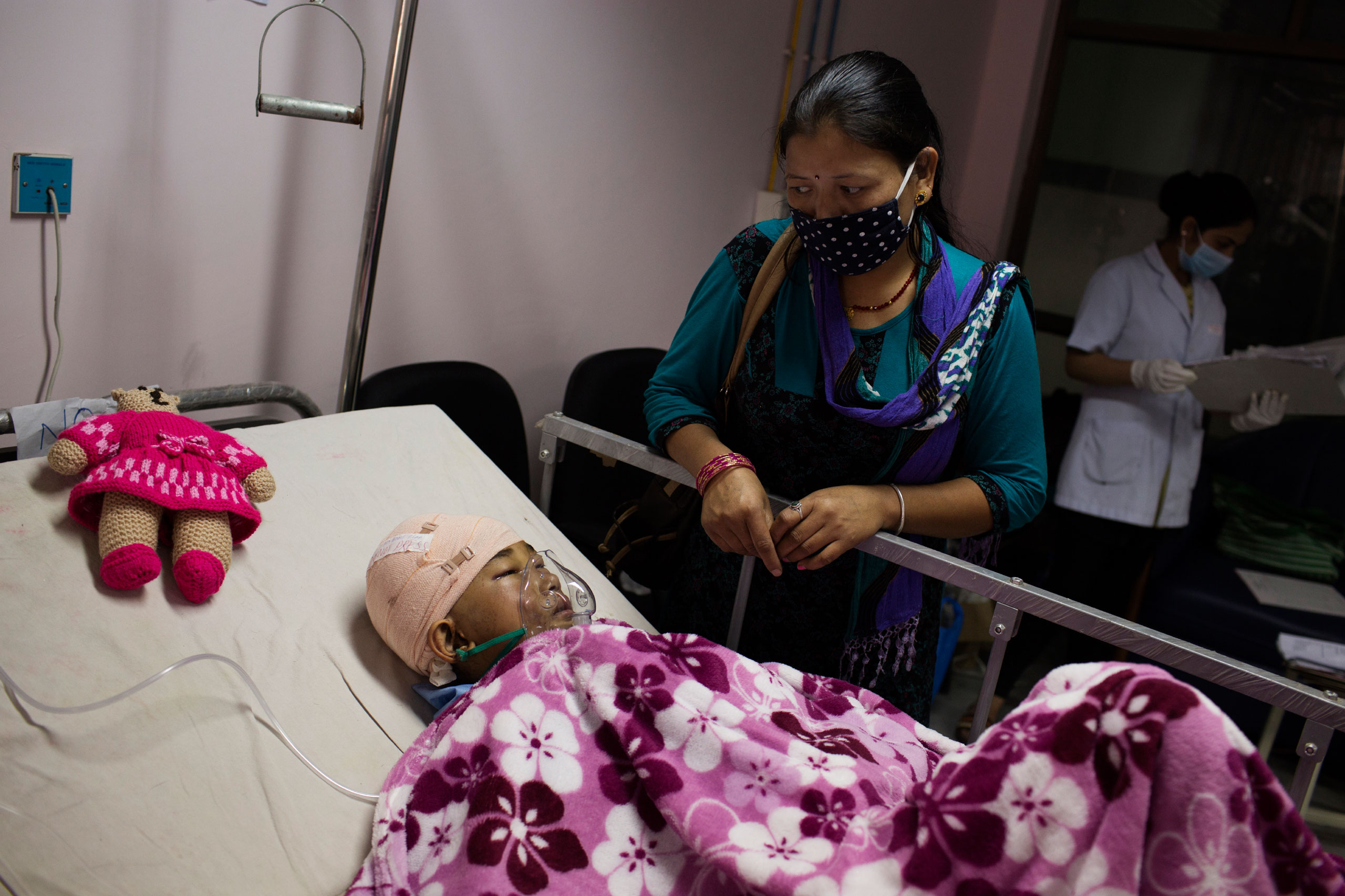 A mother looks at her son who was injured in the earthquake, at the Nepal and India Trauma Center in Kathmandu, April 29, 2015.