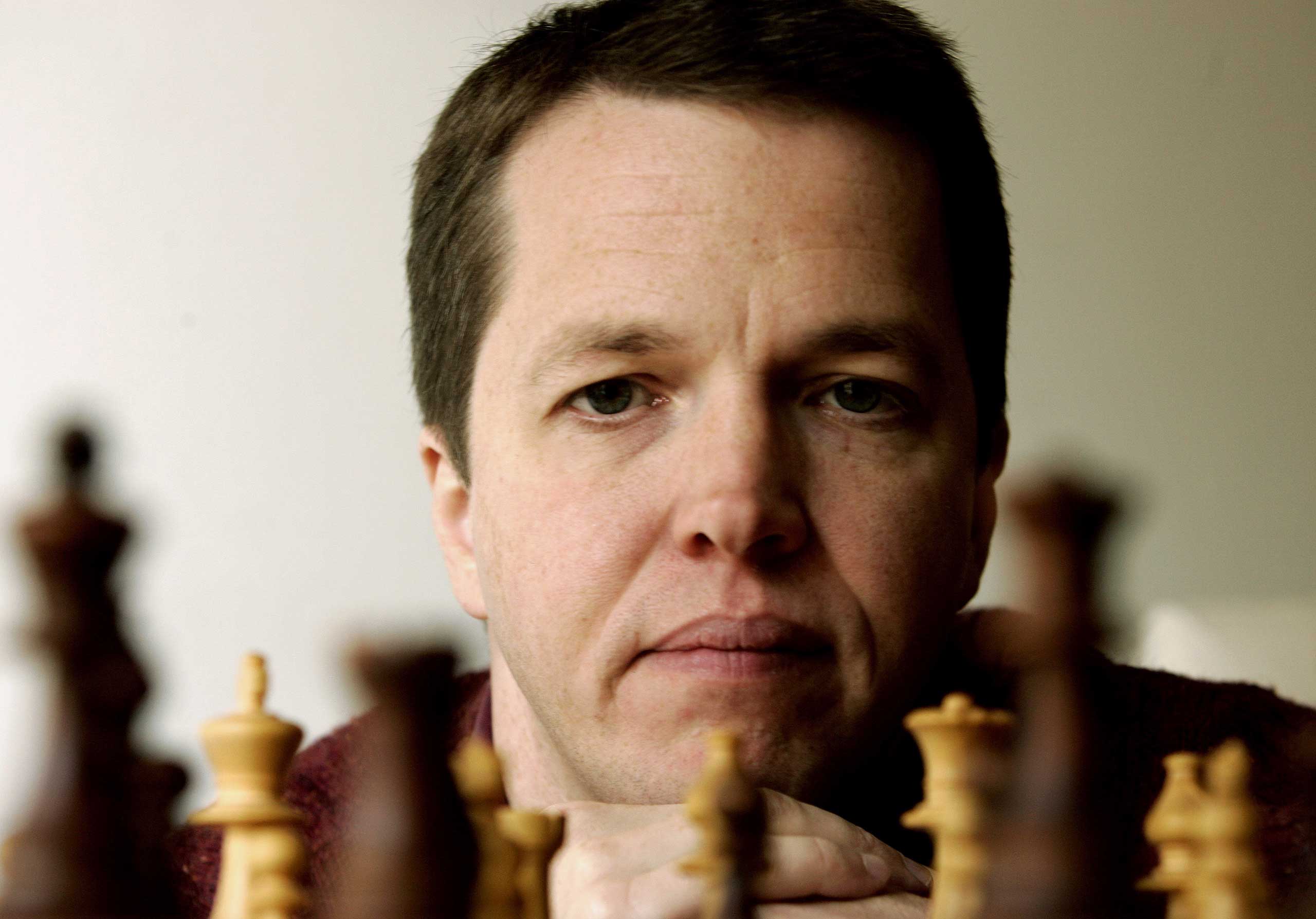 British former World Chess Championhip finalist Nigel Short looks at a chess board in his home in Athens November 4, 2005.