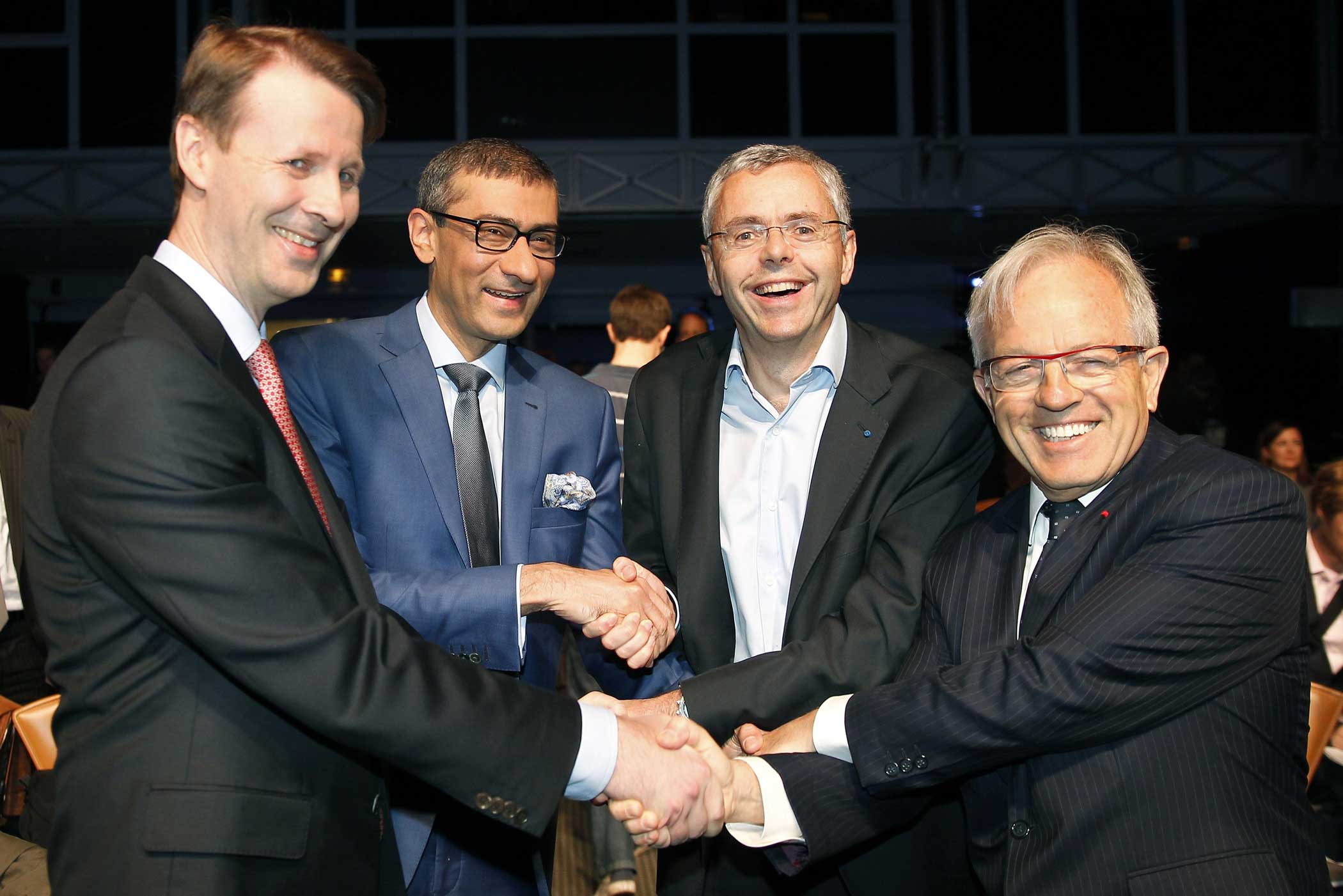 Nokia's chairman Risto Siilasmaa, Nokia's Chief Executive Rajeev Suri, telecommunications company Alcatel-Lucent's Chief Executive Officer Michel Combes and Alcatel-Lucent's chairman of the supervisory board Philippe Camus shake hands prior a press conference on April 15, 2015 in Paris. (Chesnot—Getty Images)