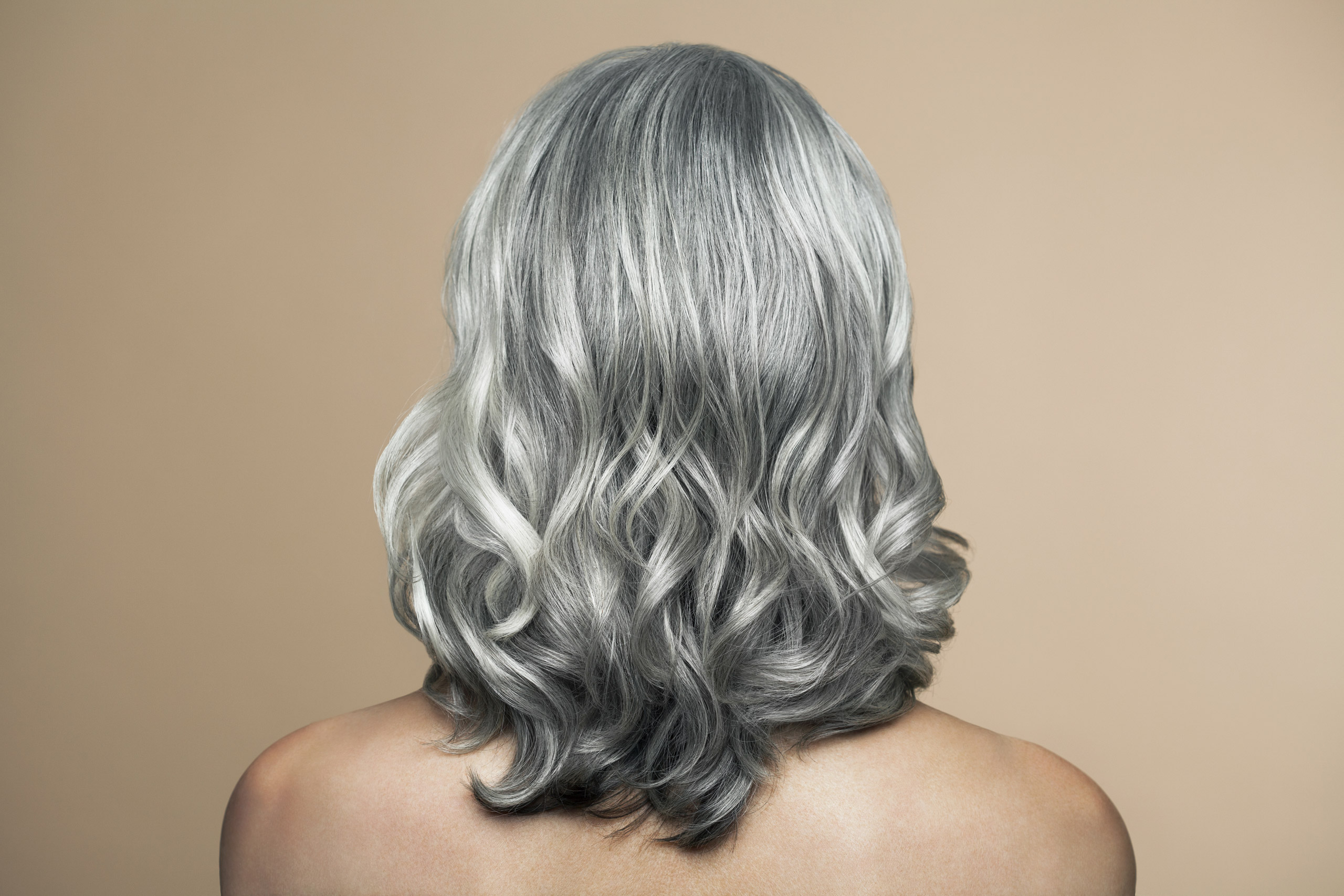 Nude mature woman with grey hair, back view.