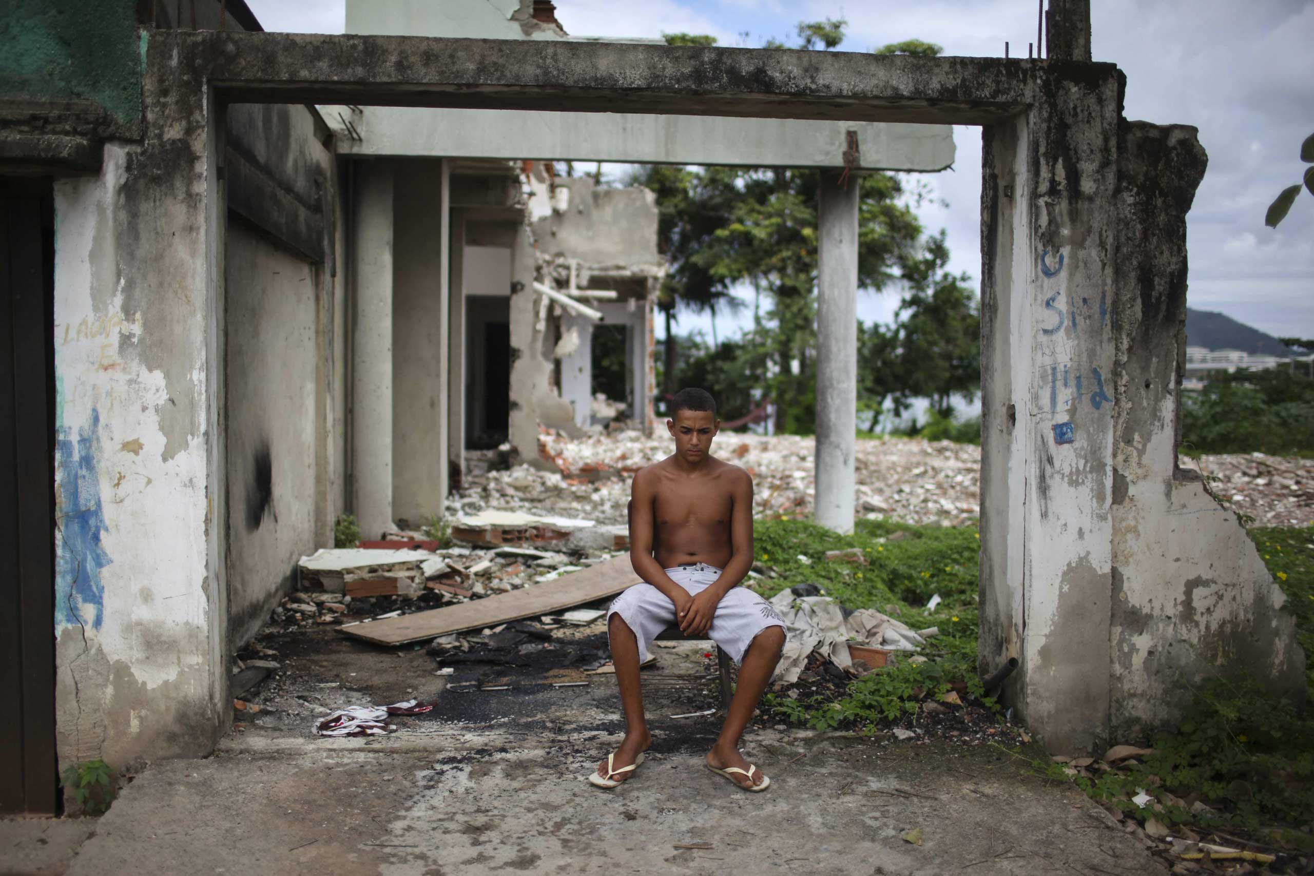 A young man rests next to a destroyed house at the shanty town Vila Autodromo, which is located close to the Olympic Park built for the Olympic Games Rio 2016, in Rio de Janeiro, Brazil, on 01 April 2015. (Antonio Lacerda–EPA)