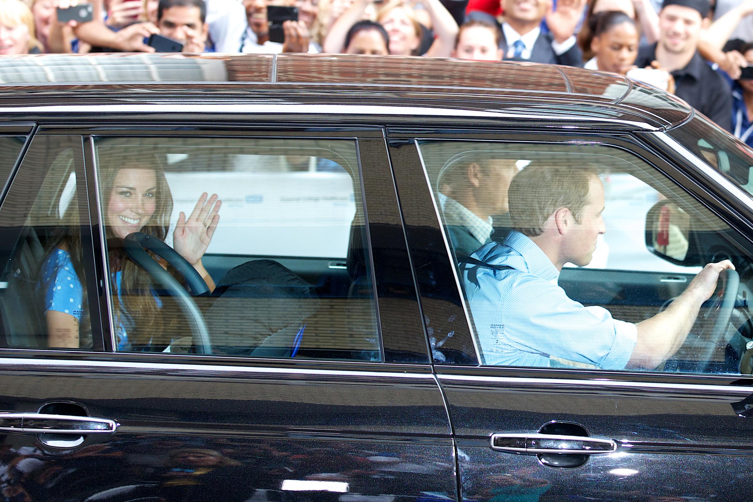 Catherine, Duchess of Cambridge (L) waves as she is driven by her husband, William, the Duke of Cambridge away from Lindo Wing of St Mary's Hospital in London on July 23, 2013. Her baby was born on Monday afternoon weighing eight pounds six ounces (3.8 kilogrammes). The baby, titled His Royal Highness, Prince (name) of Cambridge, is directly in line to inherit the throne after Charles, Queen Elizabeth II's eldest son and heir, and his eldest son William. AFP PHOTO / ANDREW COWIE (Photo credit should read ANDREW COWIE/AFP/Getty Images)