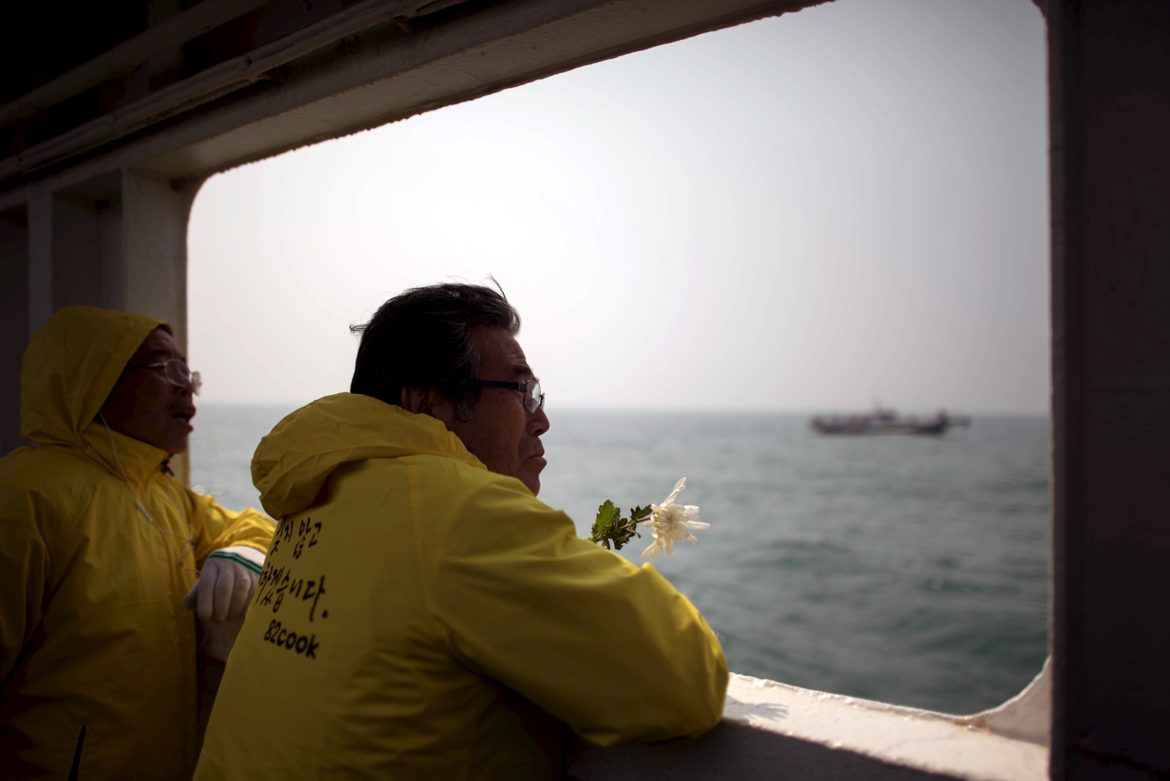 A relative of a victim of the Sewol ferry disaster holds a flower as he stands on the deck of a boat during a visit to the site of the sunken ferry, off the coast of South Korea's southern island of Jindo