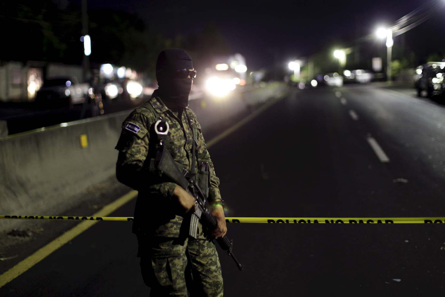 An army soldier guards a crime scene after eight people were shot dead in Quezaltepeque